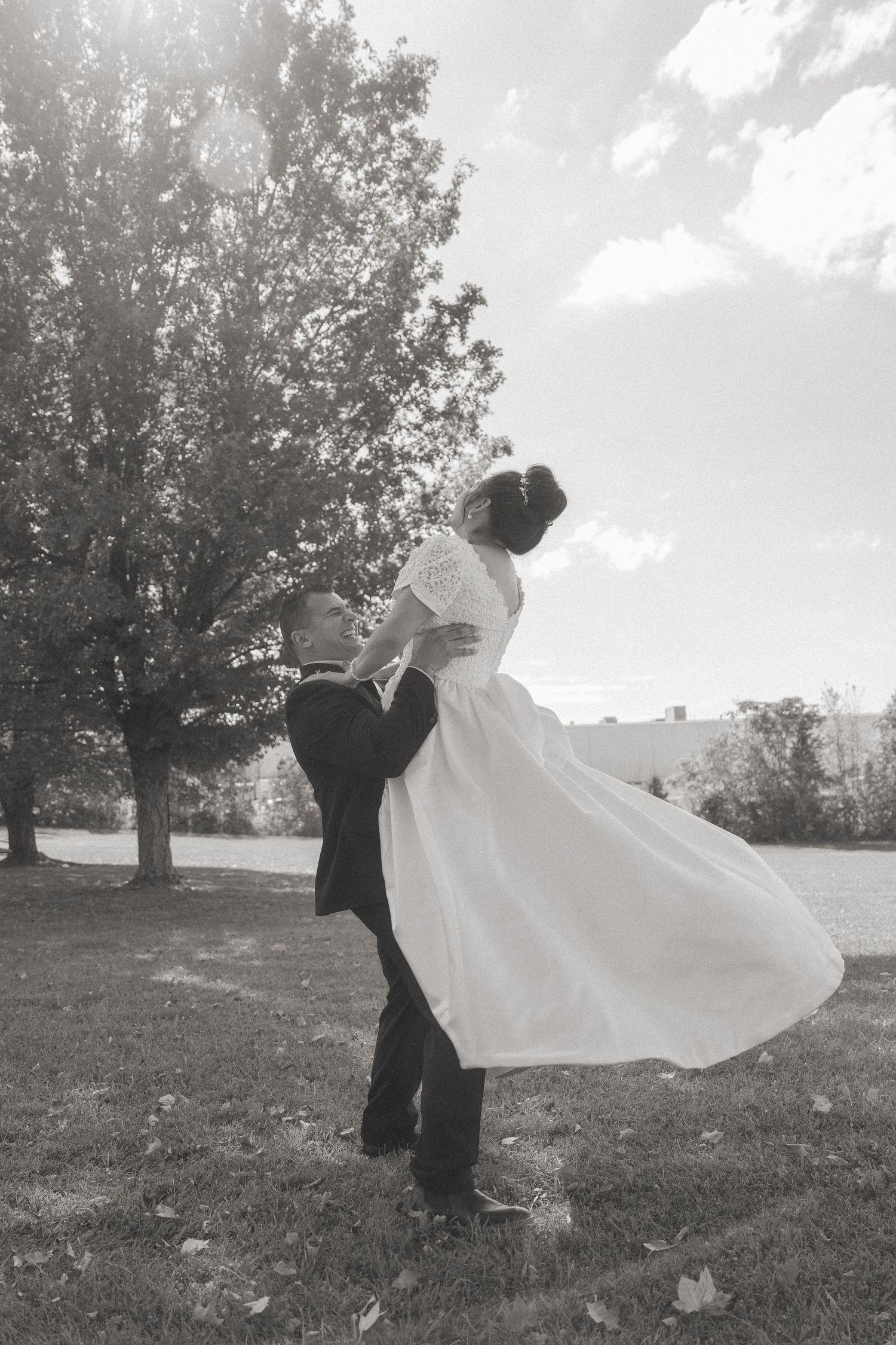 Black and white photo of newlyweds dancing in an outdoor setting.