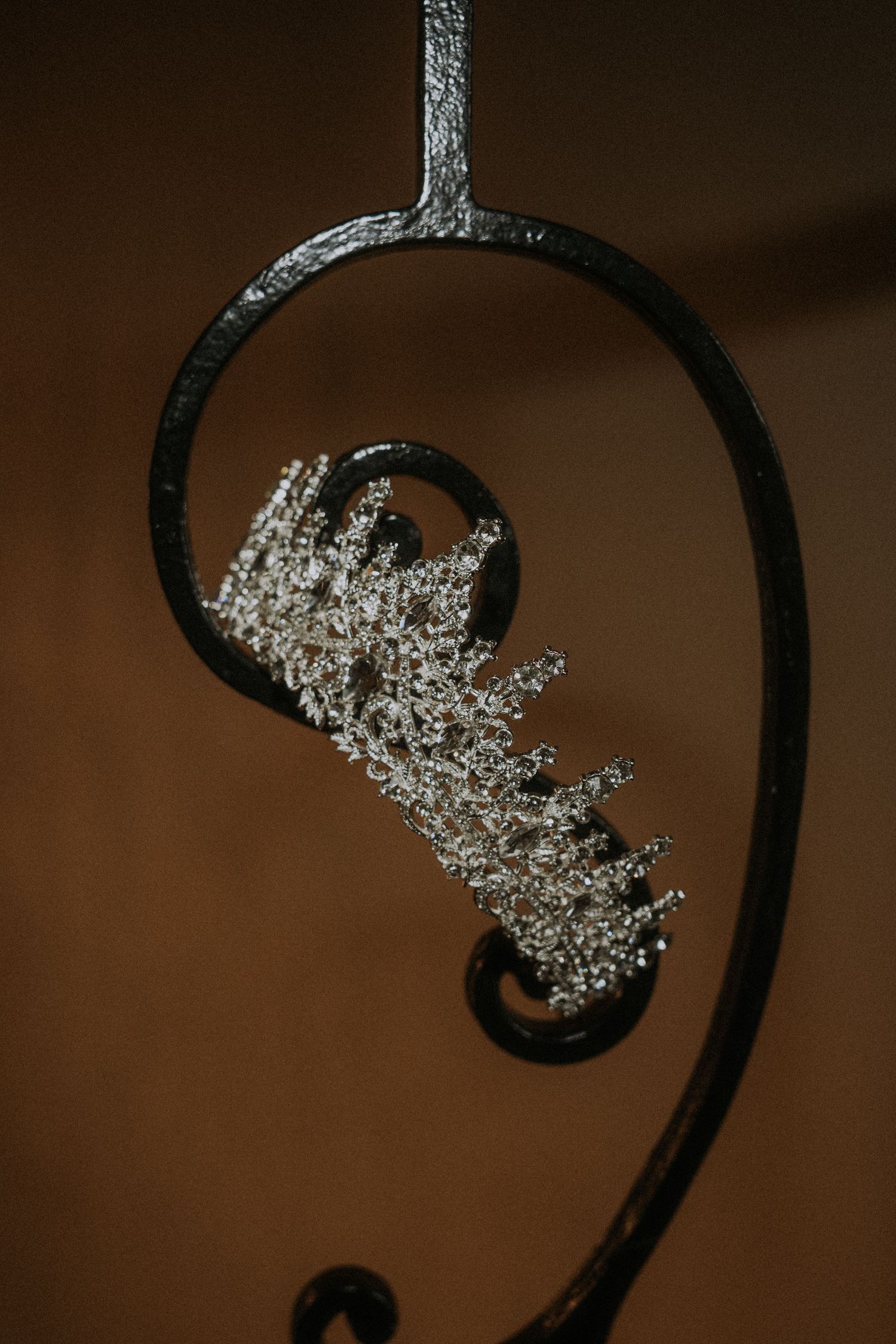Crystal bridal tiara hanging on ornate black iron wedding decor.