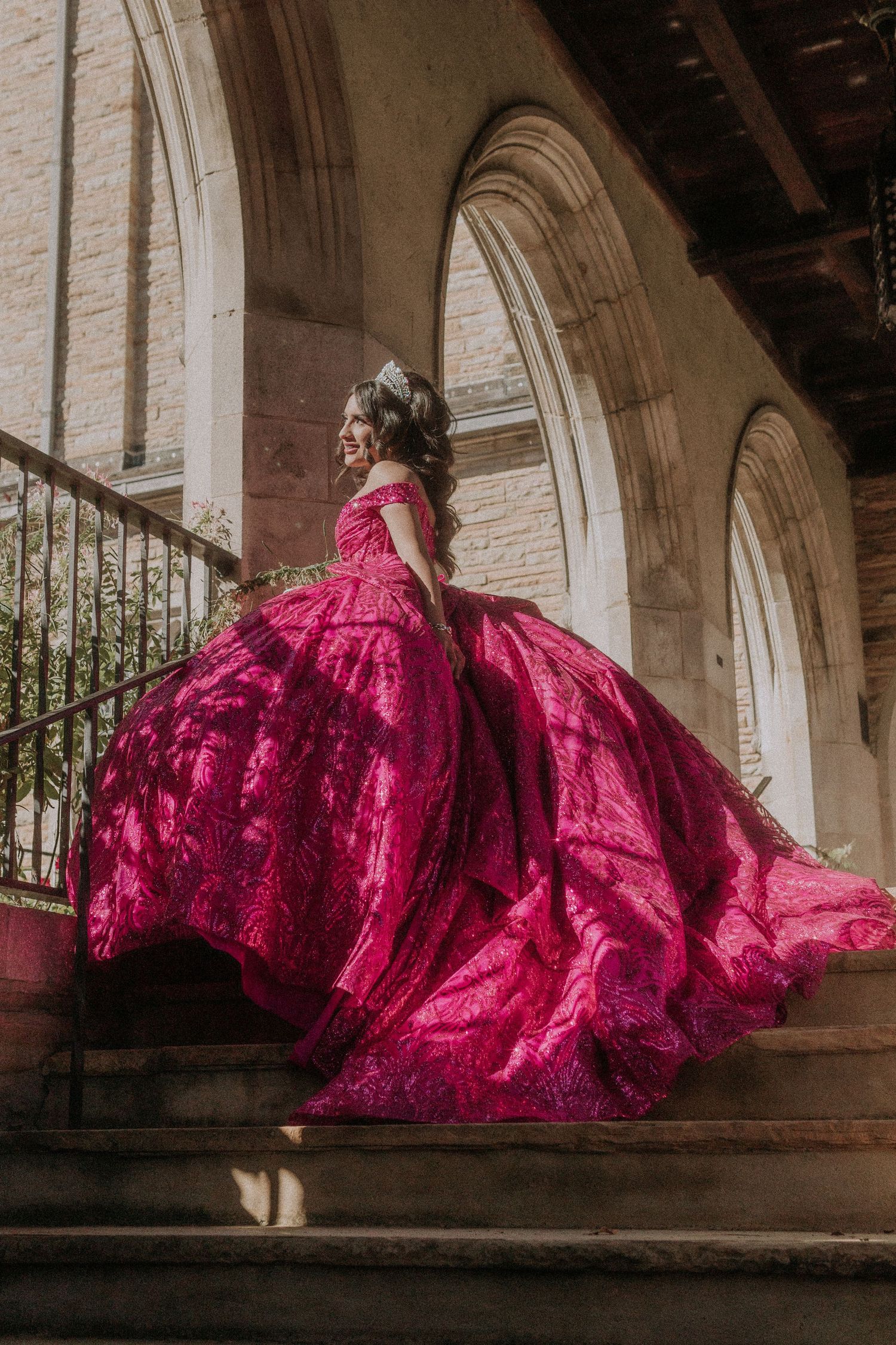 Dramatic magenta gown with full skirt photographed under classical stone archways.