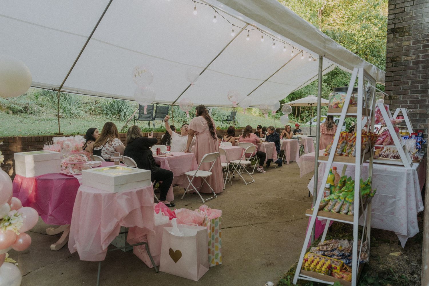 Outdoor event setup with pink and white tables under white tent canopy.