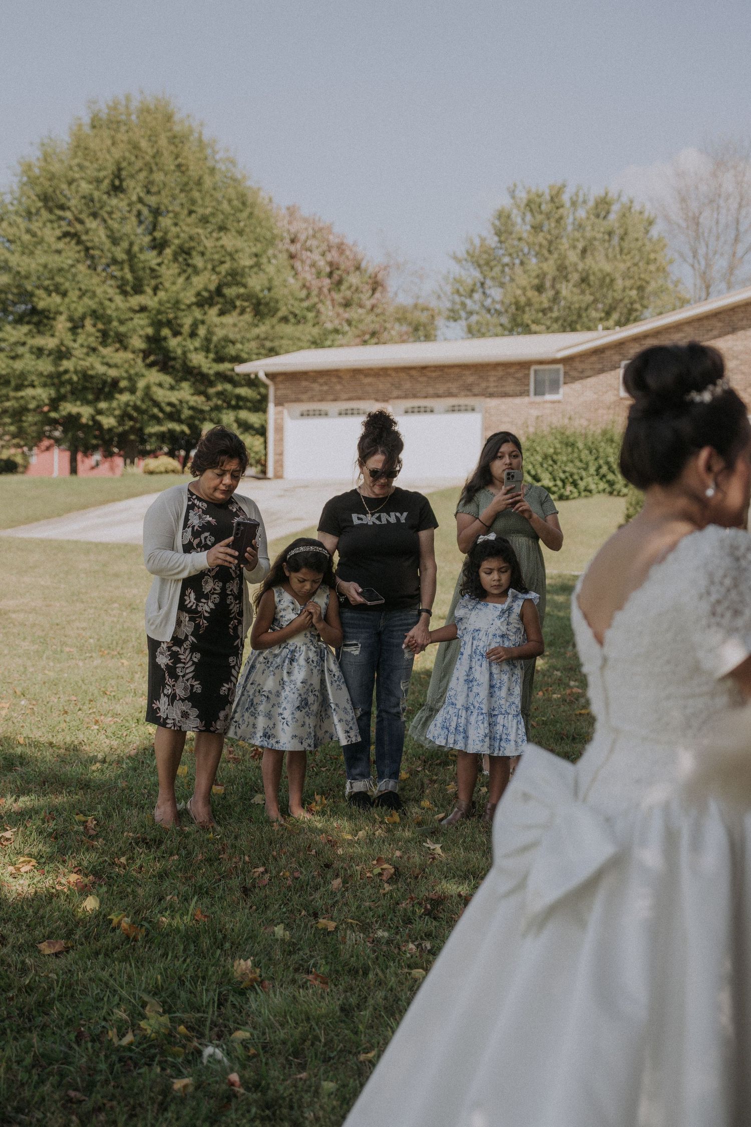 Wedding party members gathered on a grassy lawn during an outdoor ceremony.