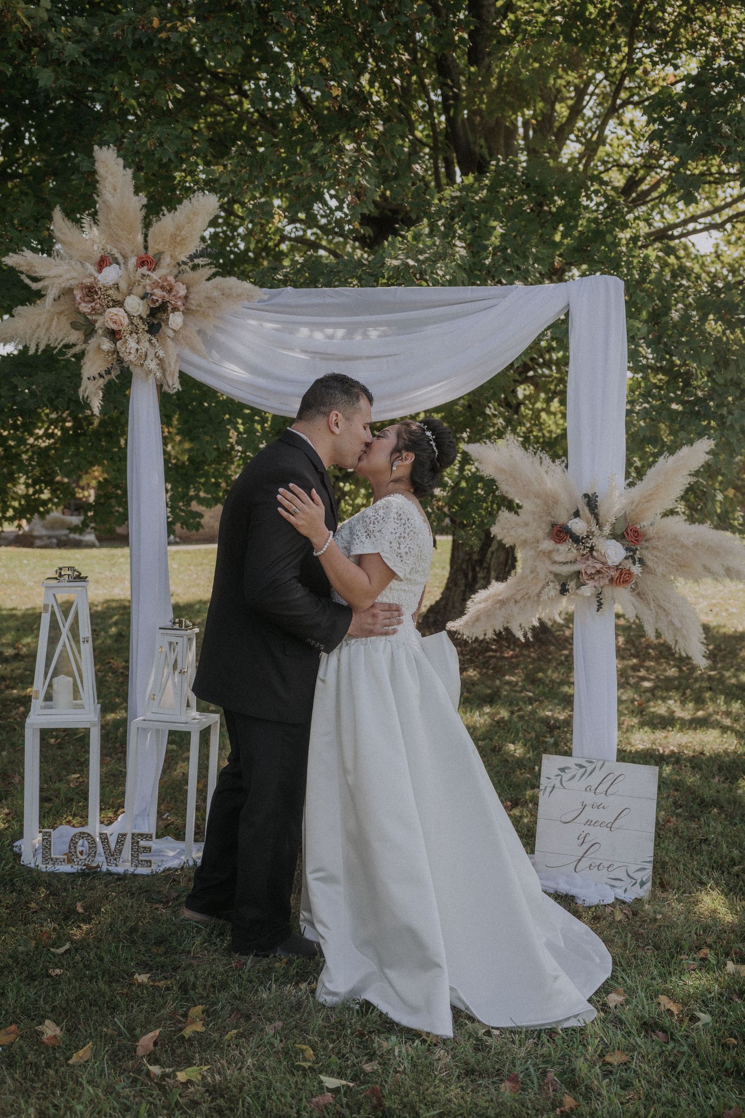 Romantic wedding ceremony moment under white draped arch with floral decorations.