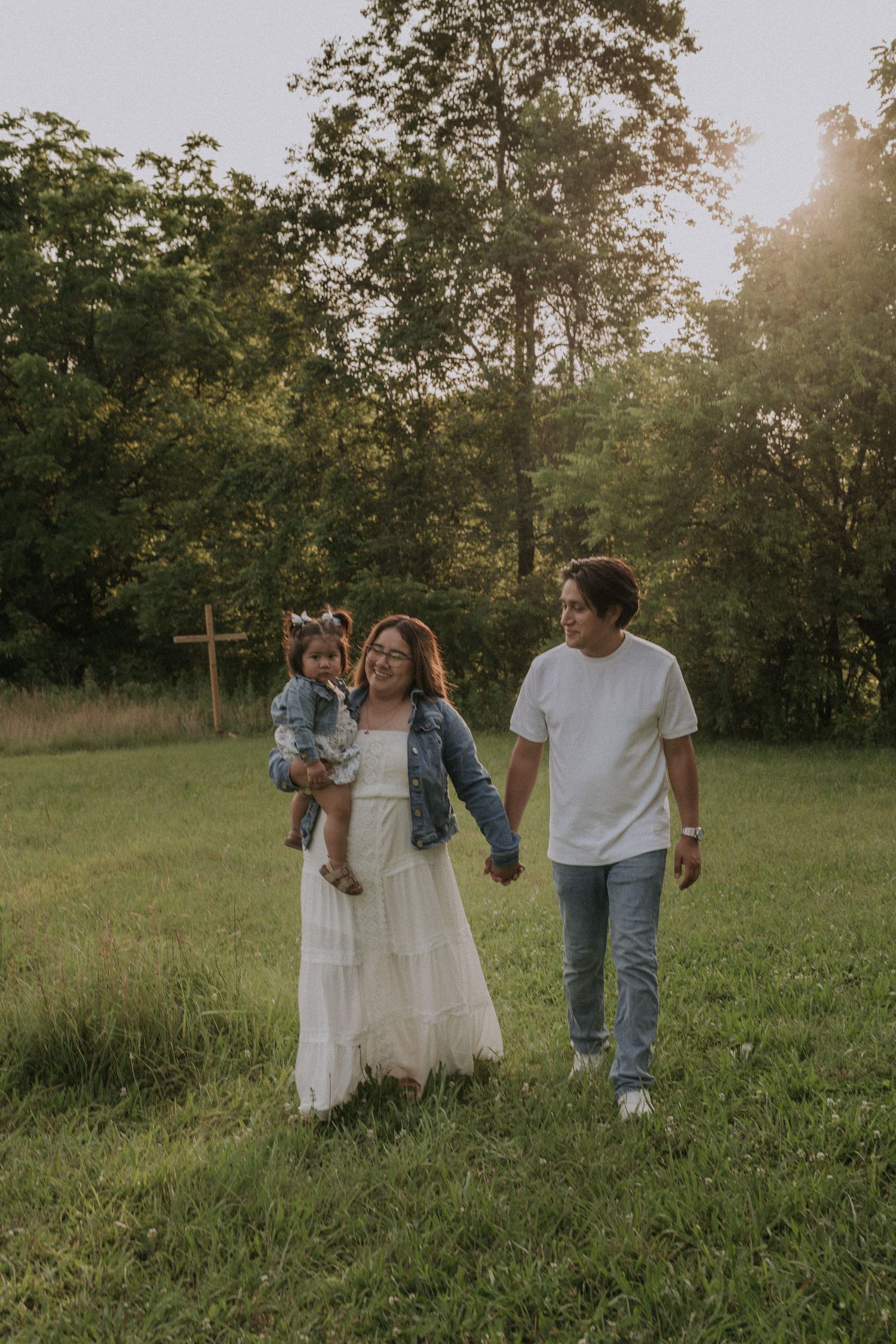 Family walking together in a sunlit meadow during golden hour.