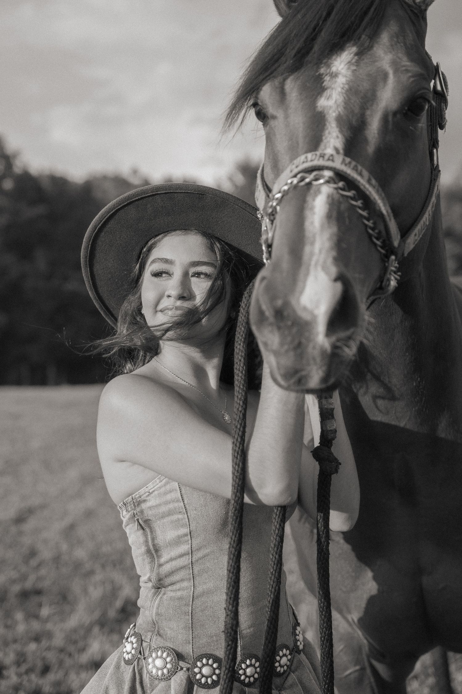 Artistic black and white portrait with a horse in a rustic outdoor setting.
