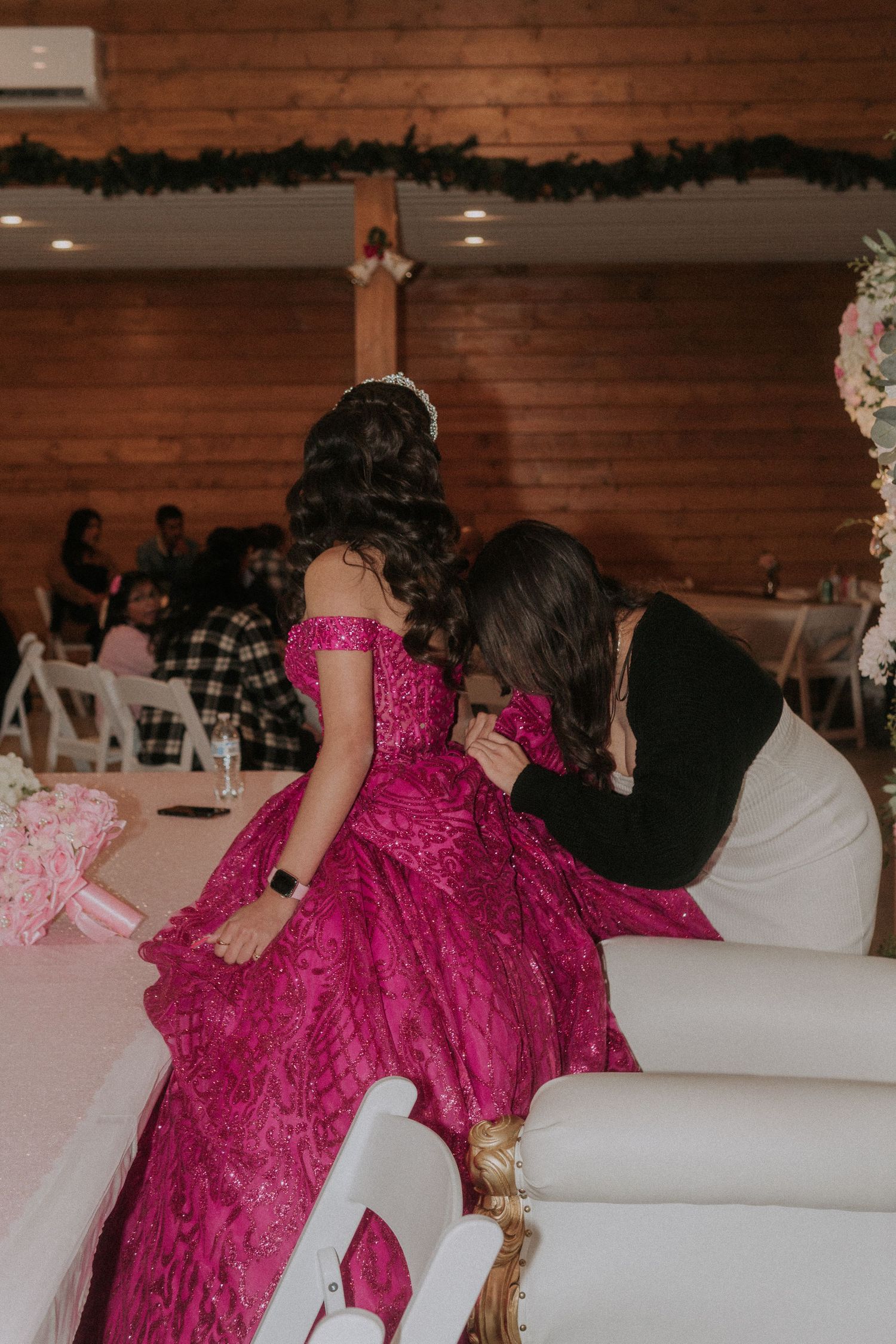 Event guests gathered in a rustic venue space with prominent hot pink formal attire.