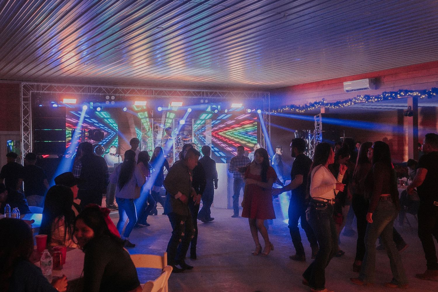 Large indoor venue with purple and blue mood lighting for a Sweet 16 party.