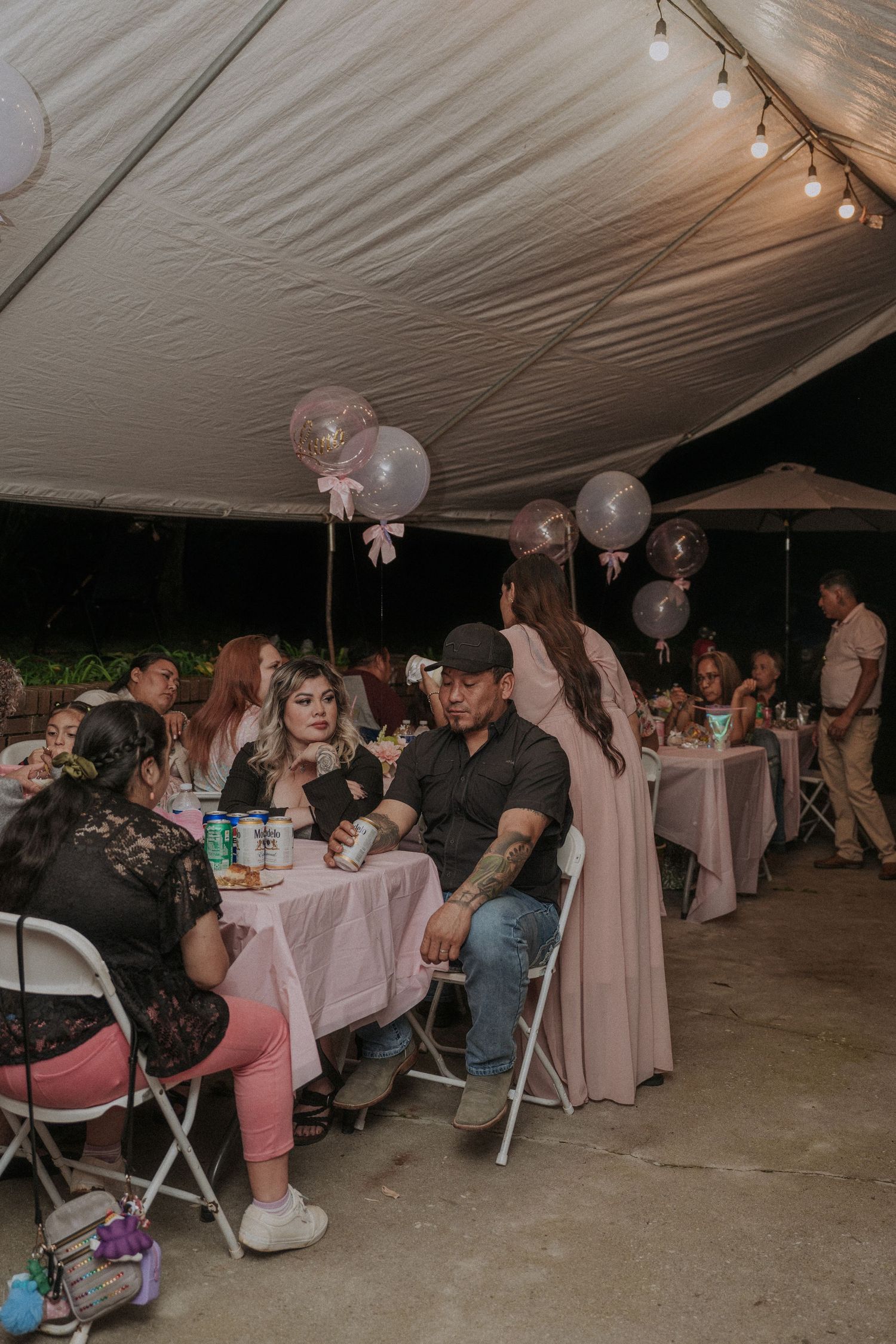 Baptism reception setup under a white tent with string lights and pink decor.