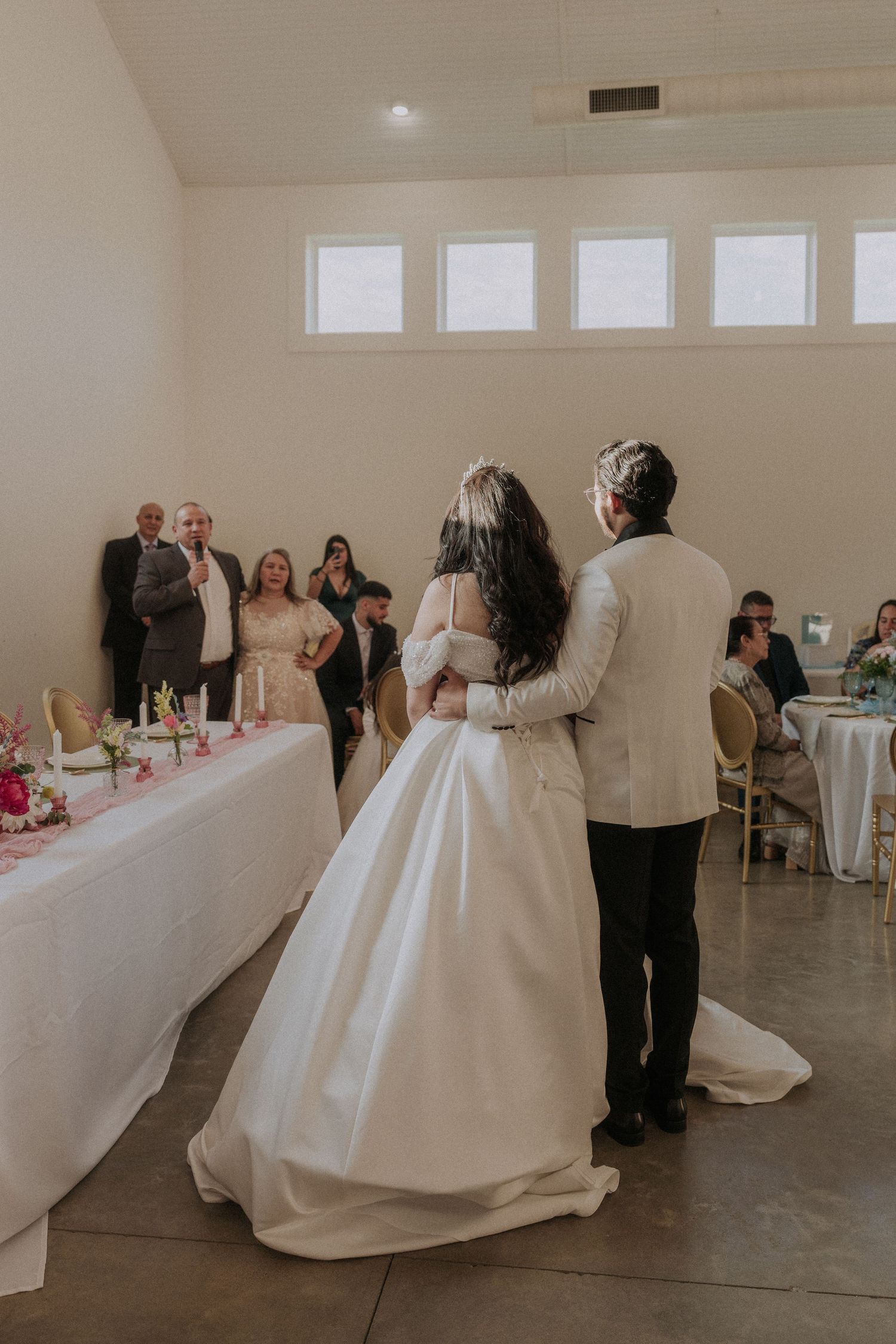 Bride and groom share first dance at wedding reception while guests watch in elegant venue.