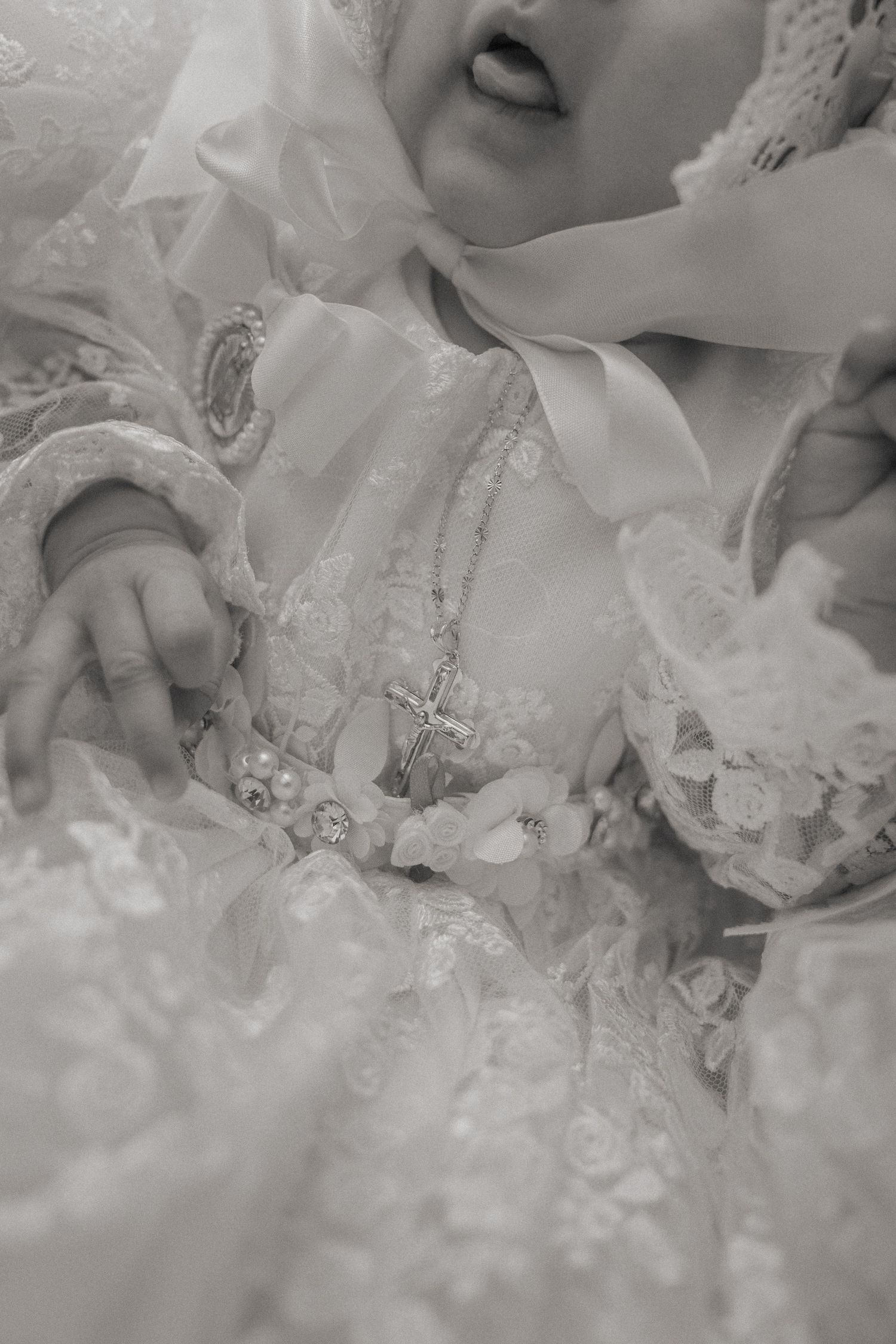 Detailed close-up of intricate white lace and embroidery on christening gown.