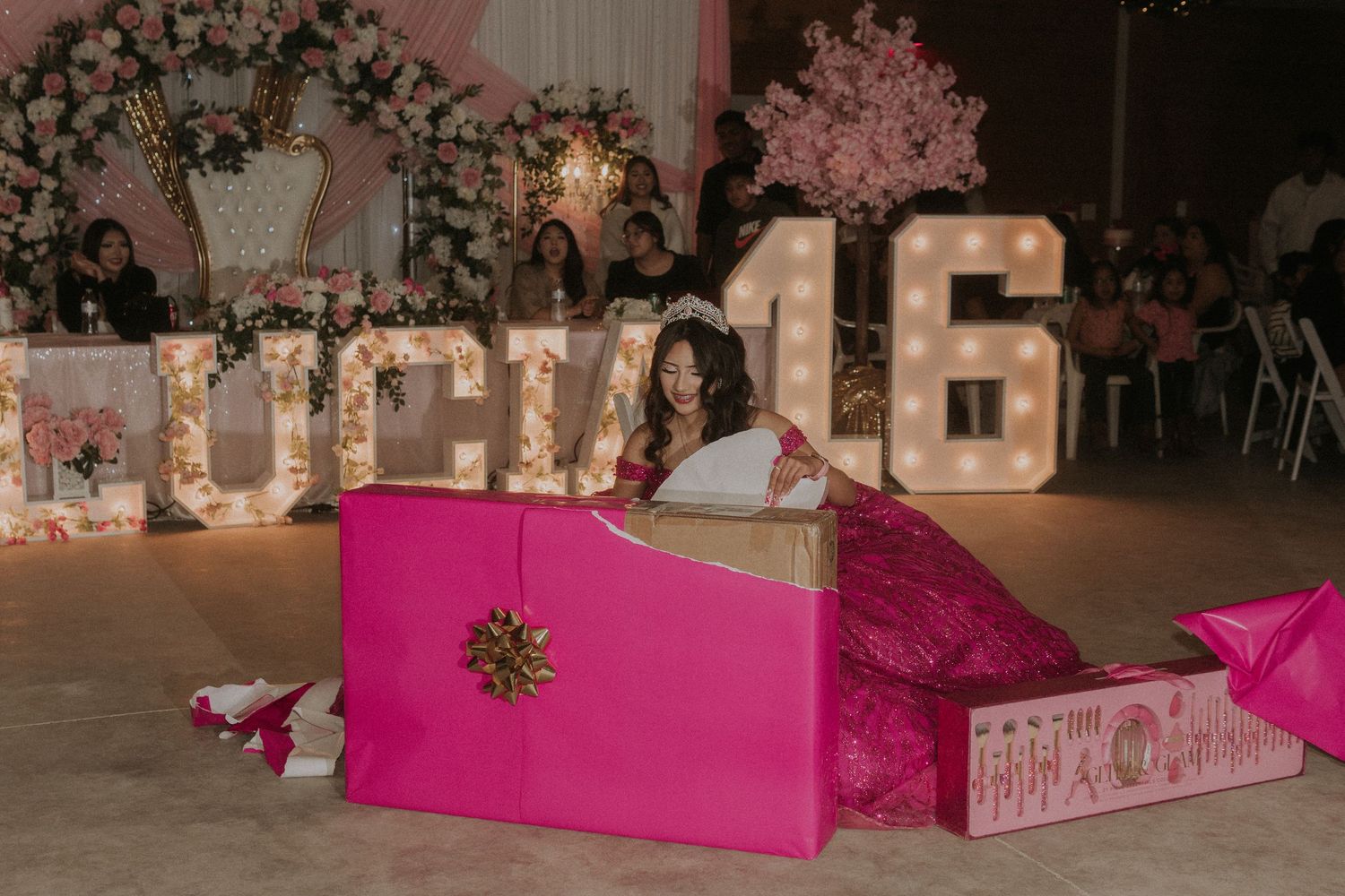 A Sweet 16 girl opens her gifts in a stunning magenta ballgown.