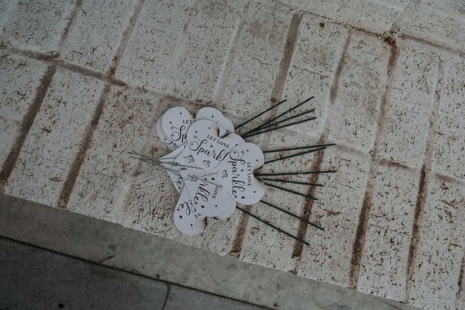 White paper flower-shaped tags with calligraphy script and metal wire stems arranged on a stone surface.