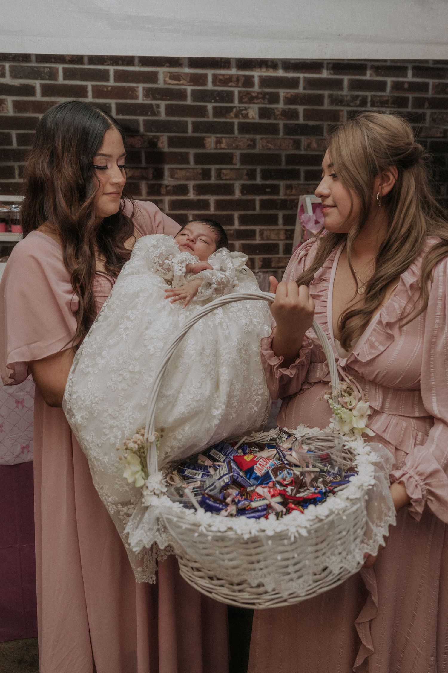 White decorative basket being passed between people wearing pink attire.