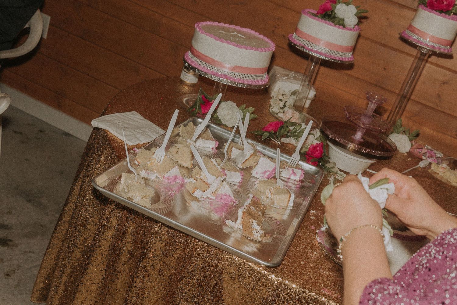 Dessert table display featuring a multi-tiered white cake with pink accents and floral decorations.
