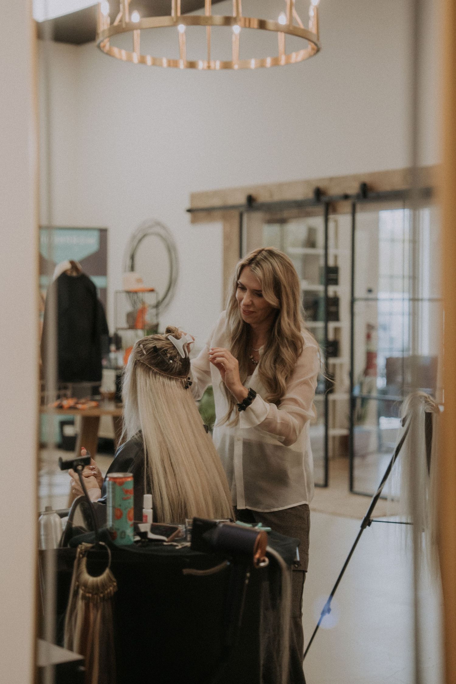 Professional hair salon workspace with stylists working under contemporary lighting fixtures.