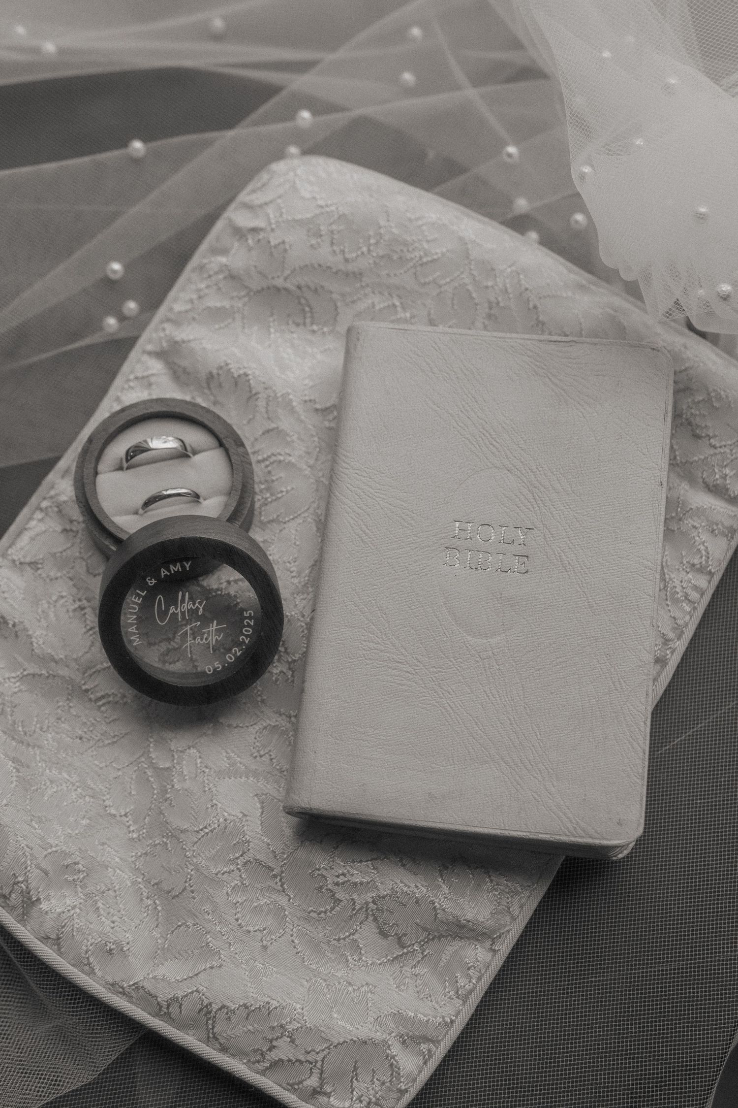 Wedding accessories including lace details and ring box arranged on dark surface.