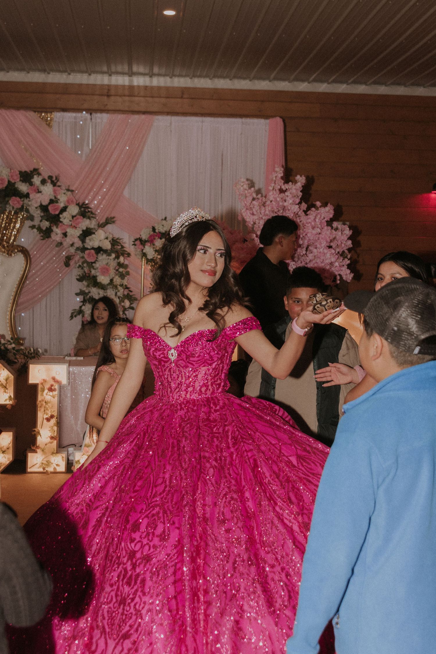 A vibrant hot pink ball gown stands out among party guests at an indoor celebration.