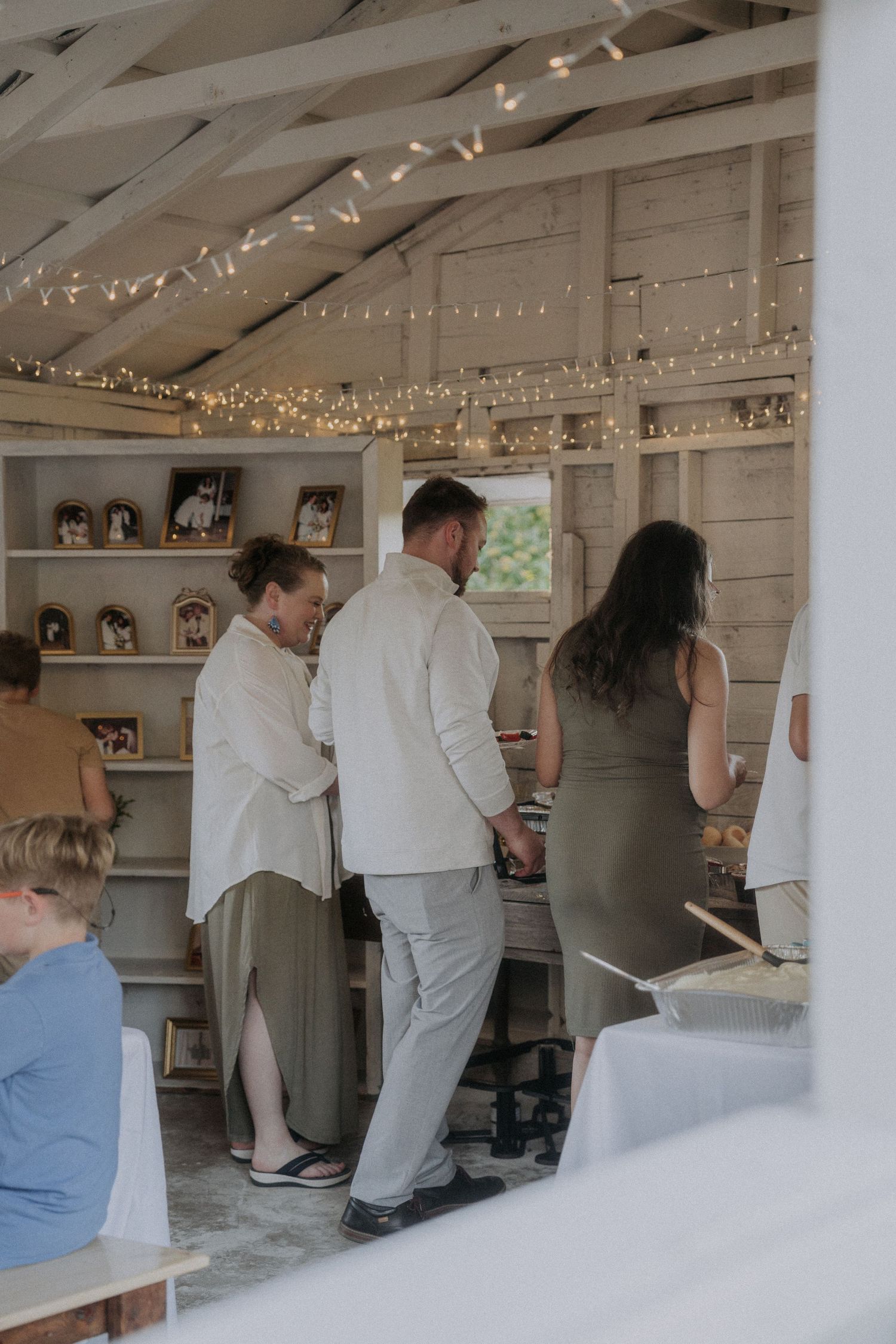 People mingling in a white-walled room decorated with string lights.
