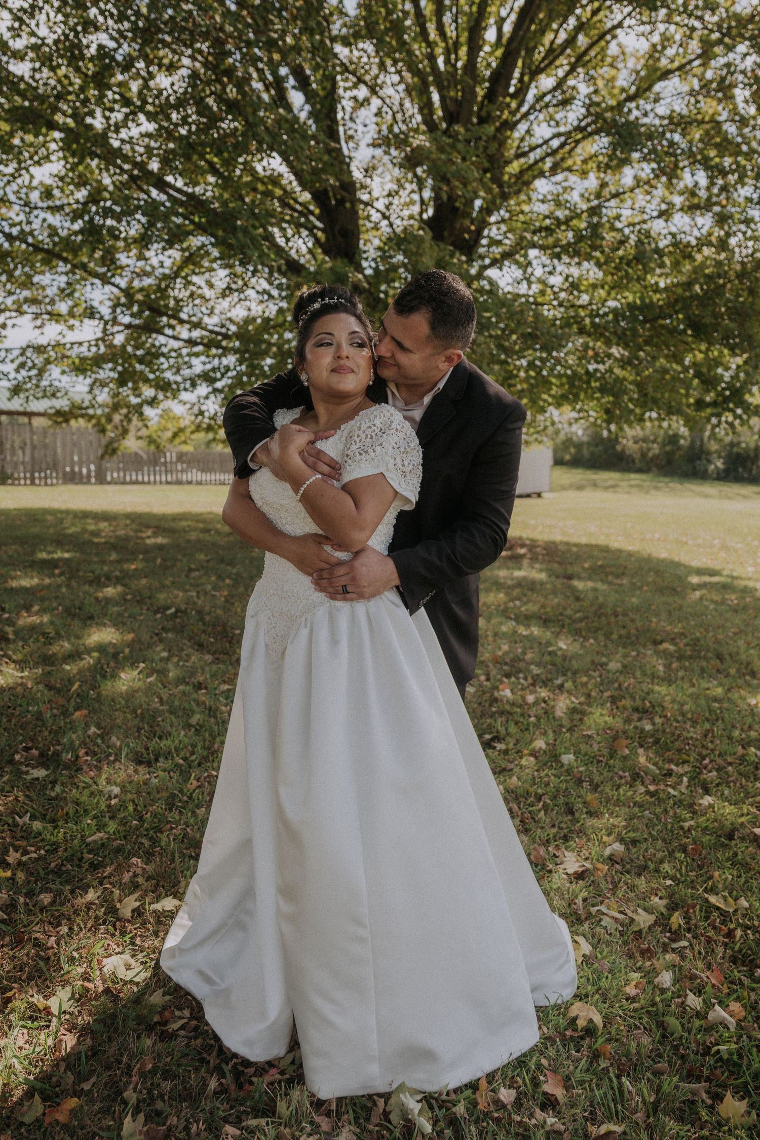A tender wedding moment captured between a couple in a sunlit garden setting.