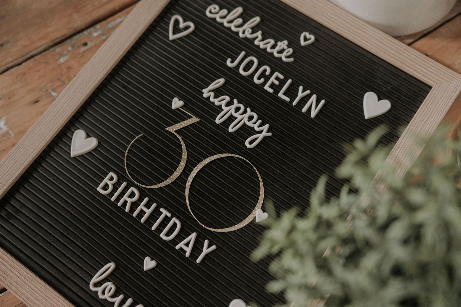 Black letterboard with white text and heart decorations against a rustic wooden background.