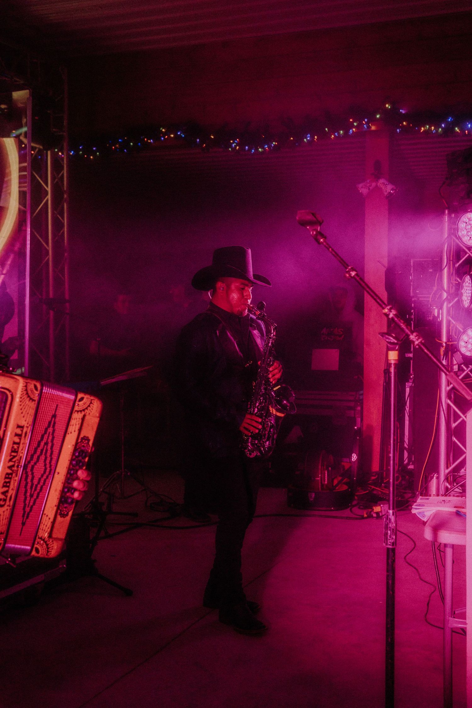 Musicians perform on stage bathed in dramatic pink and purple lighting.