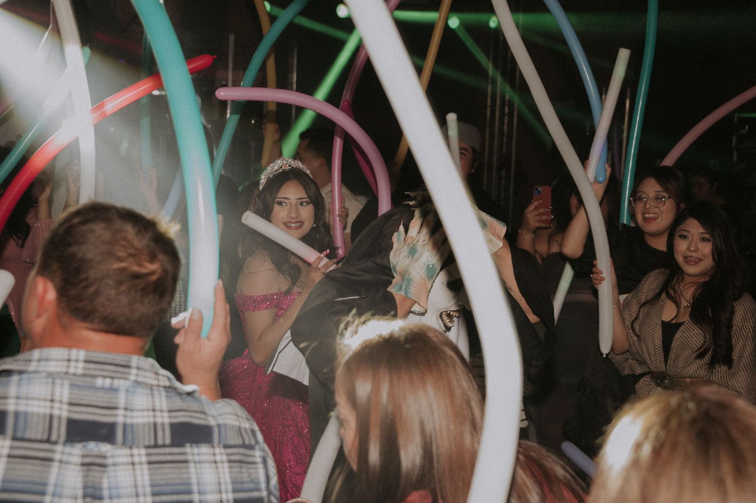 People dancing and celebrating at a Sweet 16 party with balloons creating a festive atmosphere.