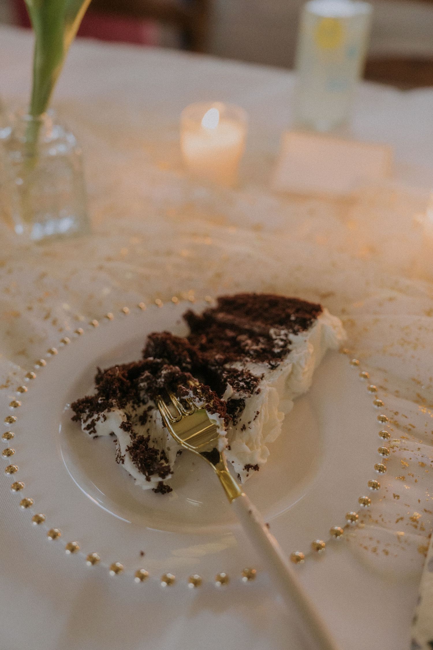 Close-up of dessert plates with chocolate crumbs on an elegant white tablecloth with decorative beading.