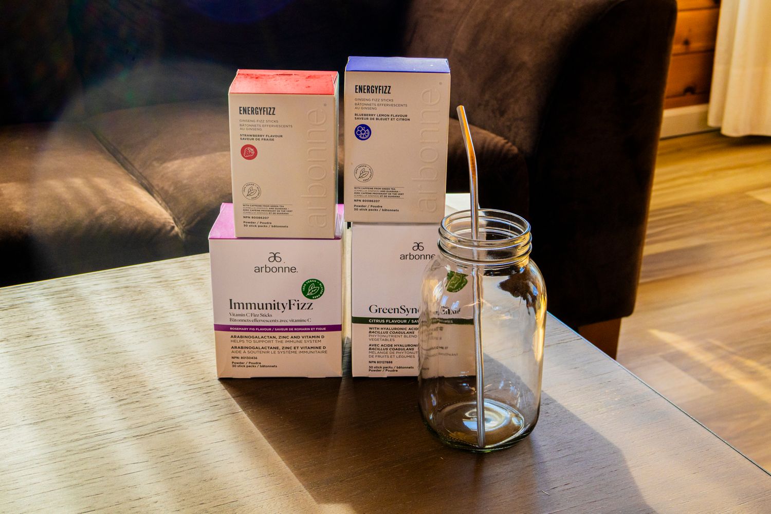Arbonne supplement boxes including ImmunityFit and ClearFut displayed on a wooden table beside a glass mason jar.