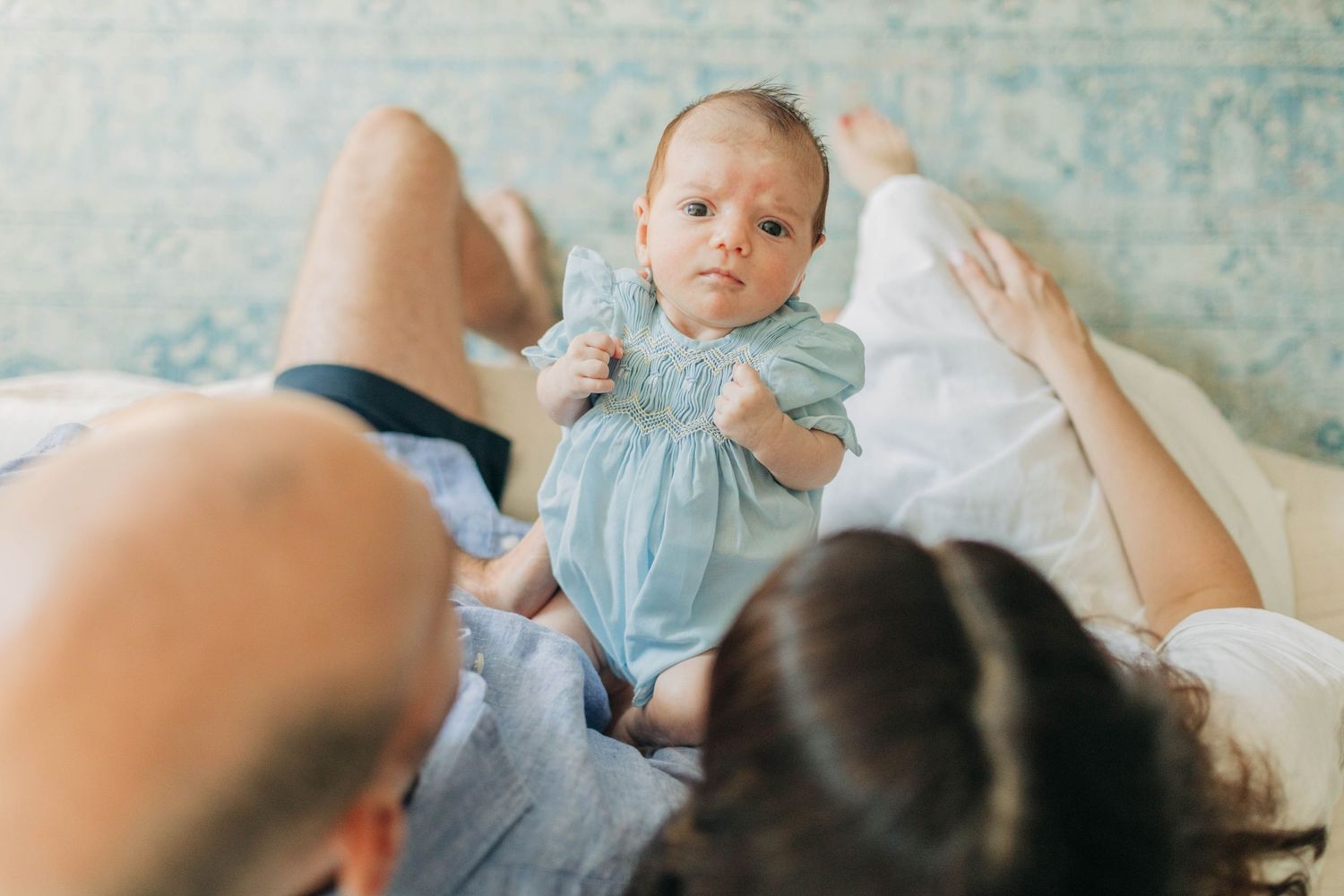 Sweet lifestyle photos of baby in light blue outfit laying on white bedding.