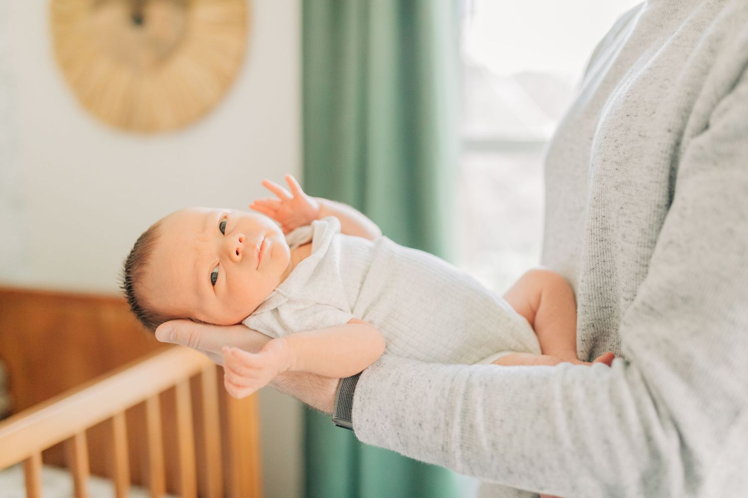 Gentle interaction between parent and baby in modern nursery setting.