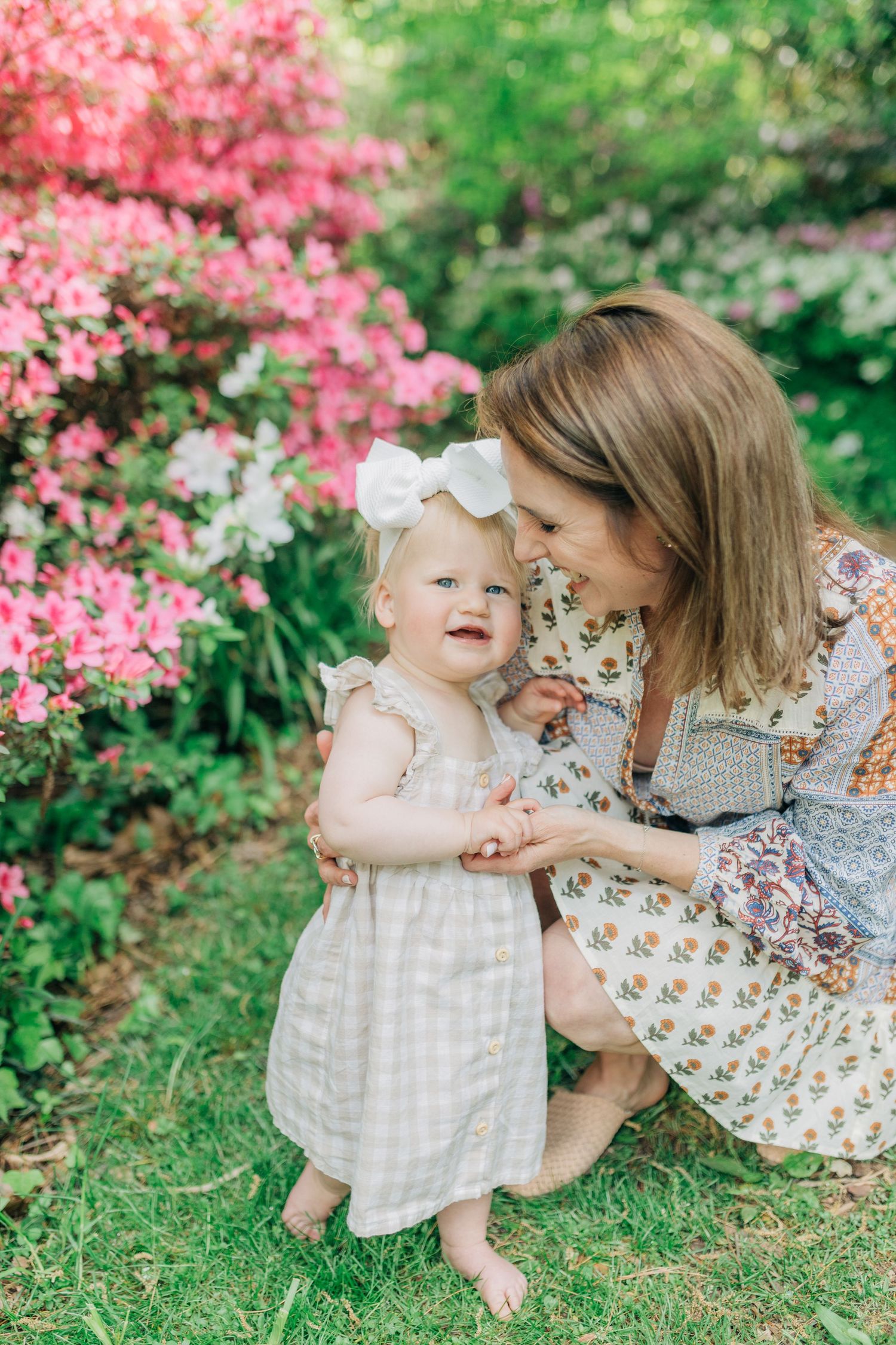 A tender moment captured in a garden with blooming pink azaleas as backdrop.