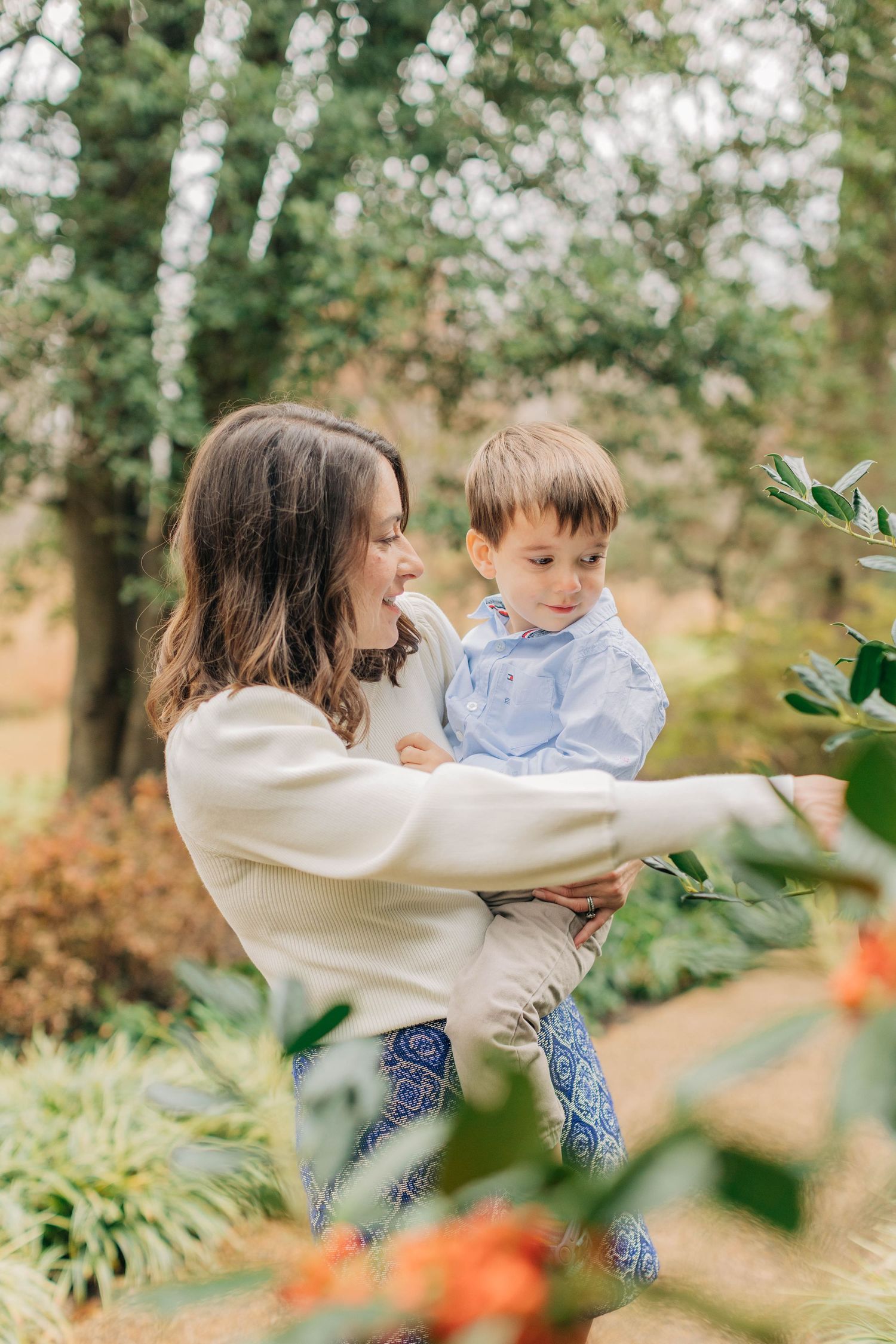 A sweet embrace between parent and child amidst blooming flowers and trees.