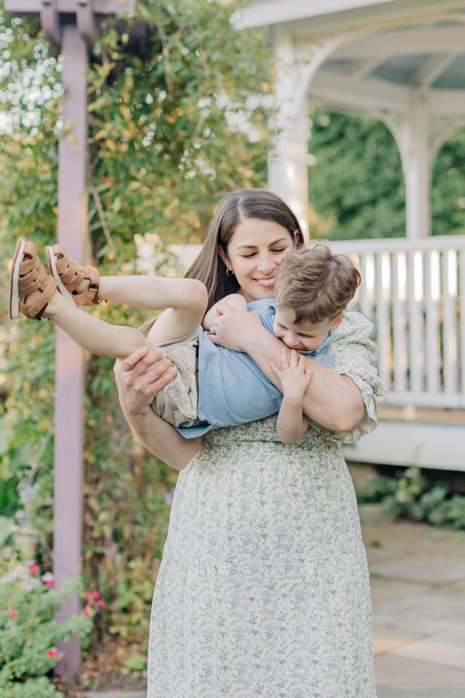 A tender moment between family members in a garden setting with white picket fence.