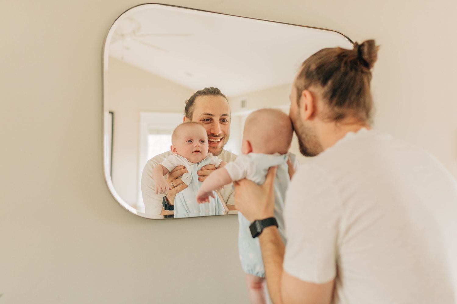 Family interacts playfully in front of wall mirror.