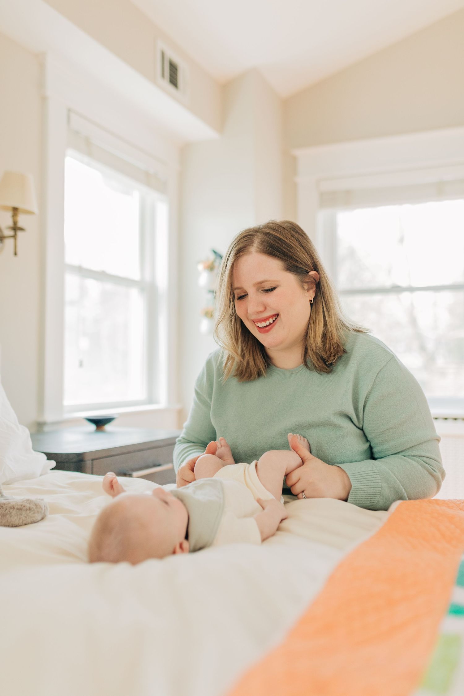 Family shares intimate bonding moment on white bedding in sunlit room.
