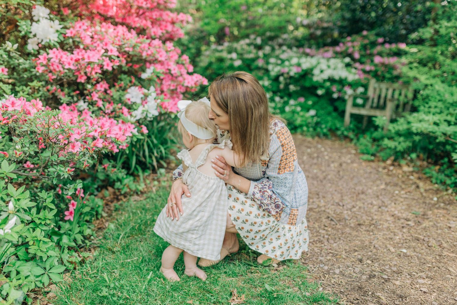 A sweet springtime moment shared on a garden path lined with blooming pink azaleas.