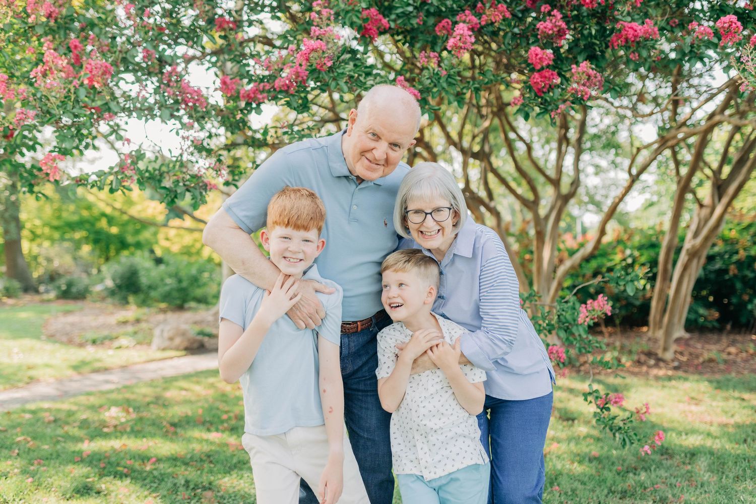 Playful family interactions photographed in front of blooming crepe myrtle trees.