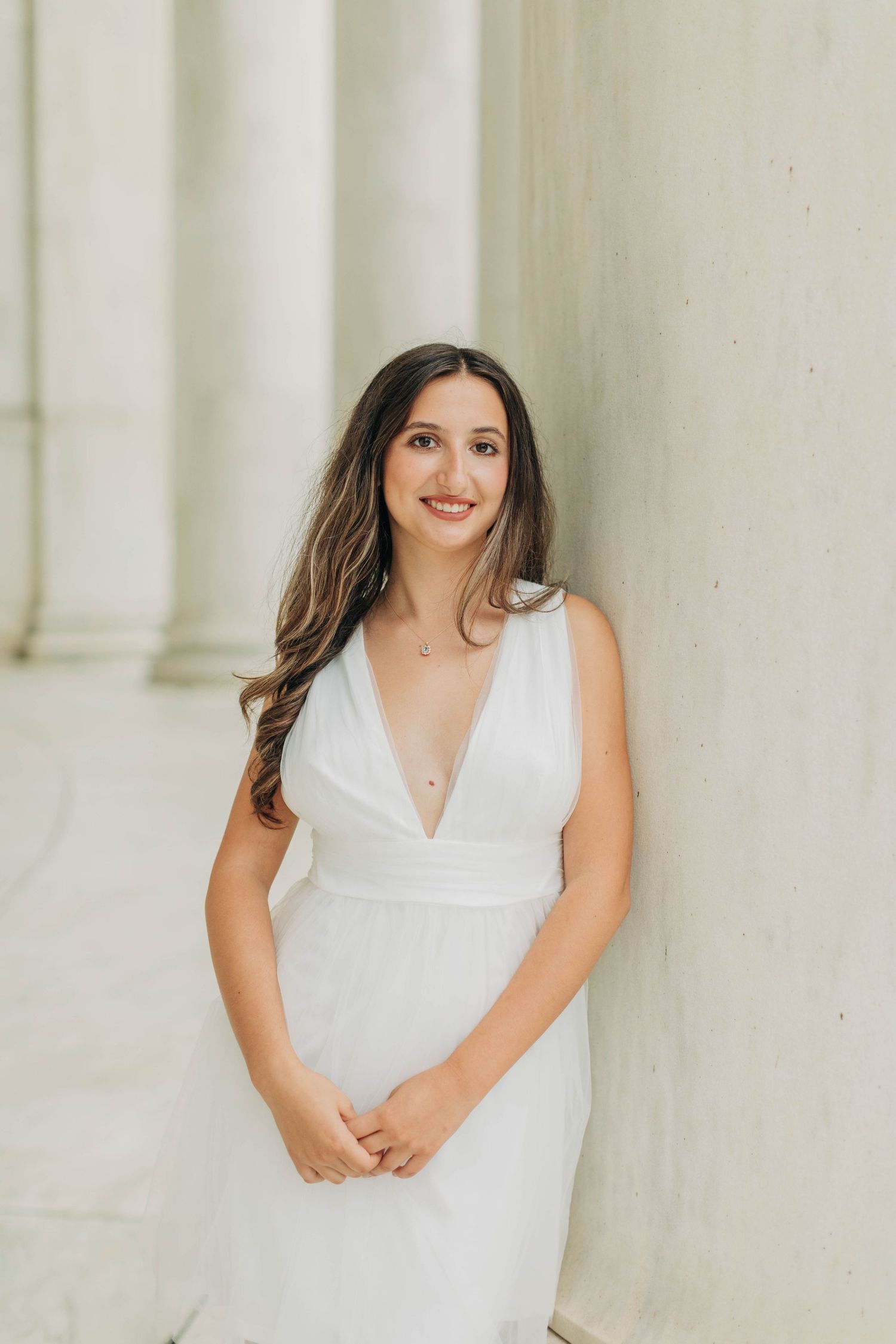 Elegant portrait session against white marble columns in a classic architectural setting.