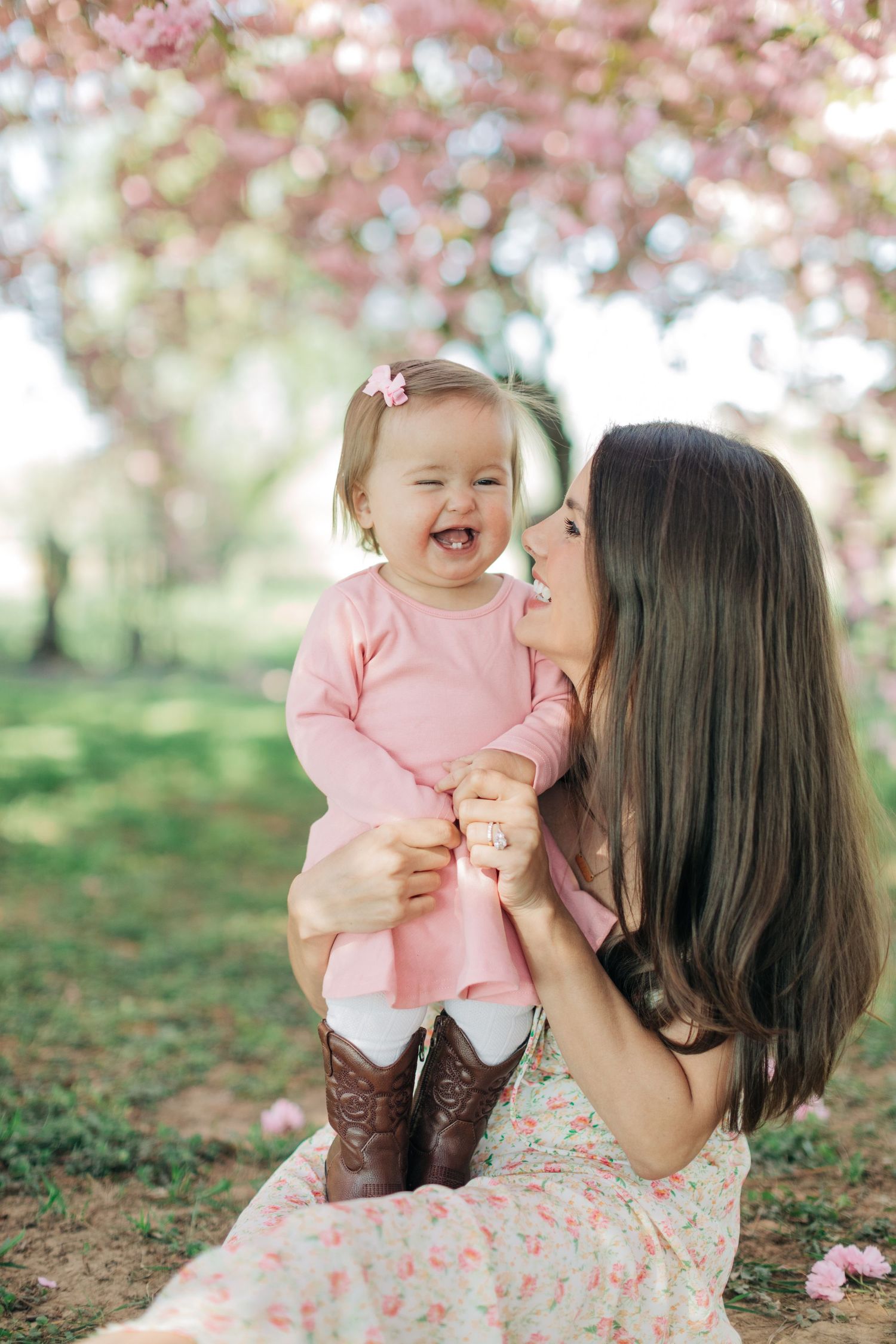A joyful moment shared under cherry blossom trees with matching pink outfits.