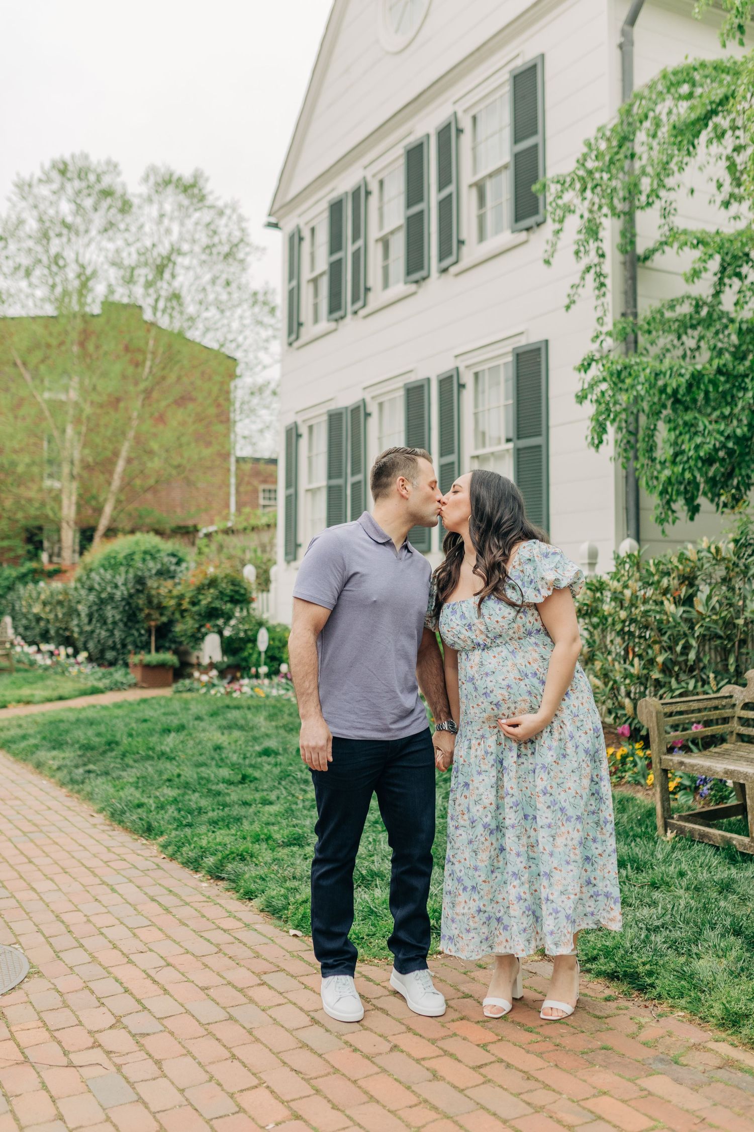 A couple poses together on a brick pathway surrounded by spring greenery.