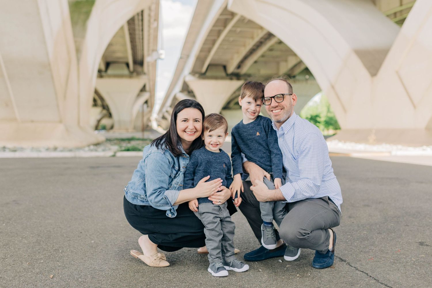 Family group portrait under modern concrete architectural structure.