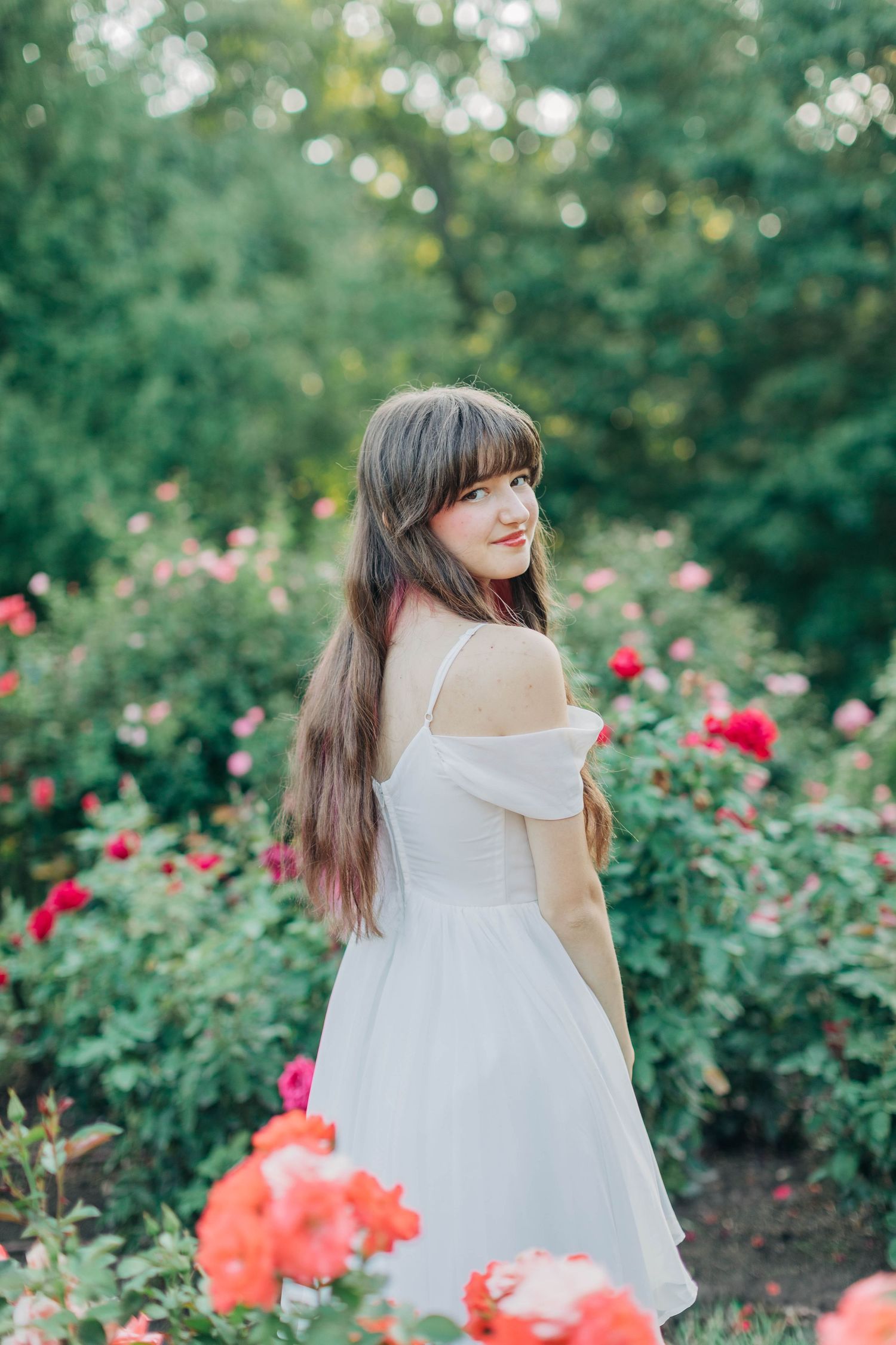 Dancing movement captured in a white dress against a backdrop of coral and red roses.
