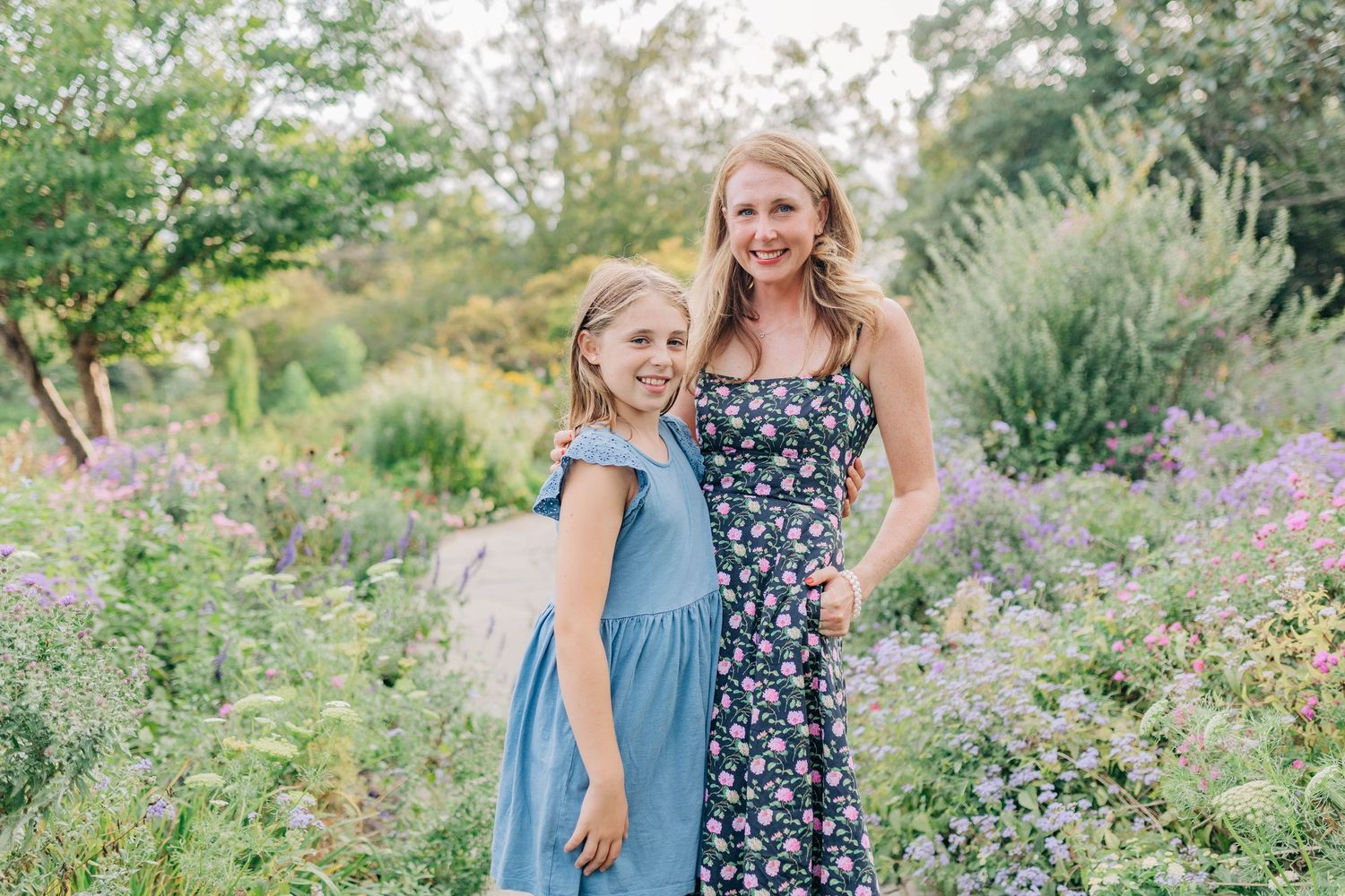 Two people share a joyful moment together in a lush garden filled with purple and green foliage.