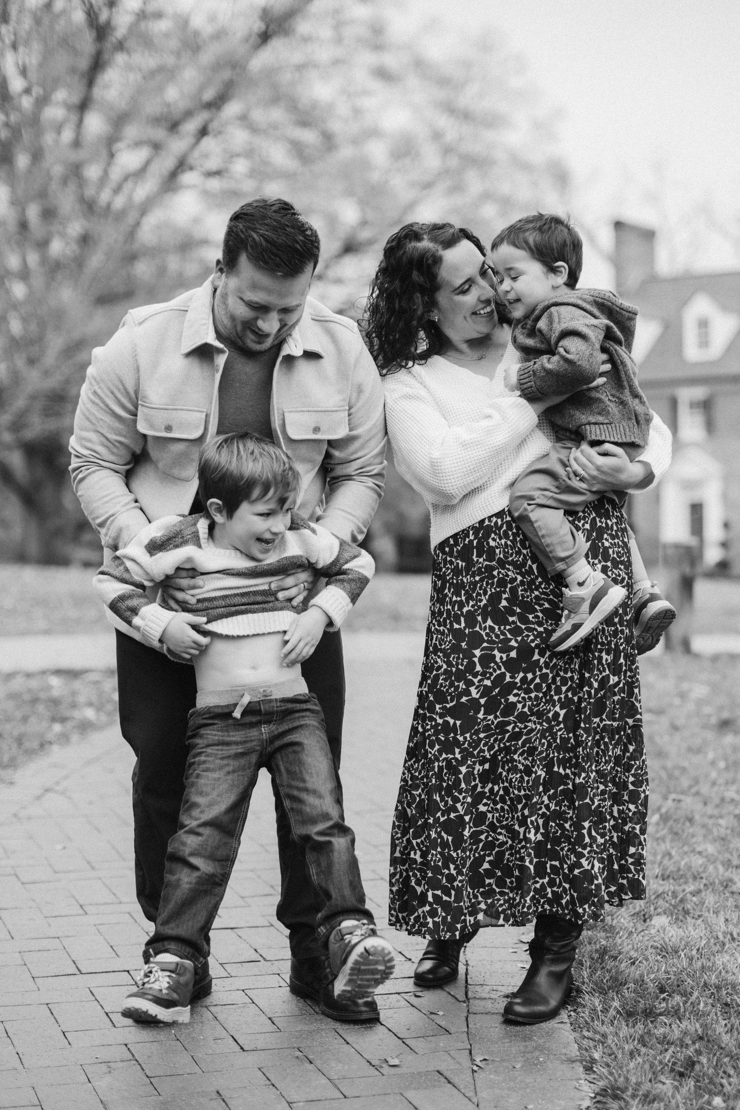 Family members share joyful embraces outdoors in black and white photography.