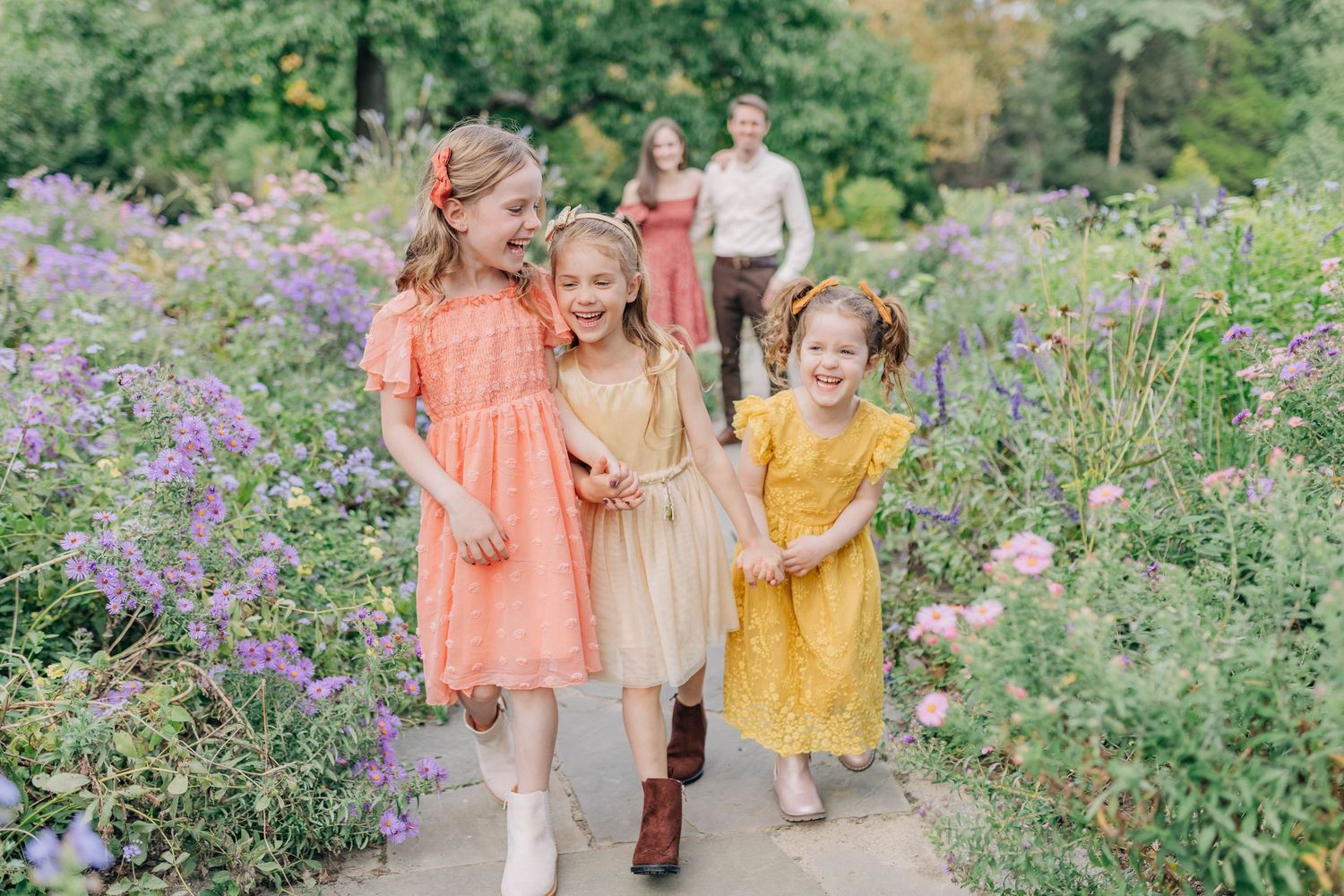 A beautiful garden photoshoot with coordinated coral and yellow dresses among purple wildflowers.