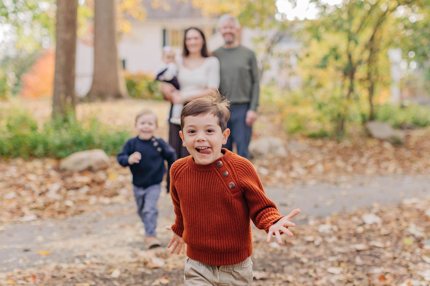 Child in rust-colored sweater playing outdoors in autumn scenery.
