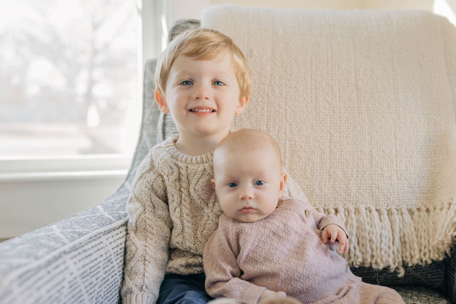Family lounging together on a bright white couch in a sunlit living room.