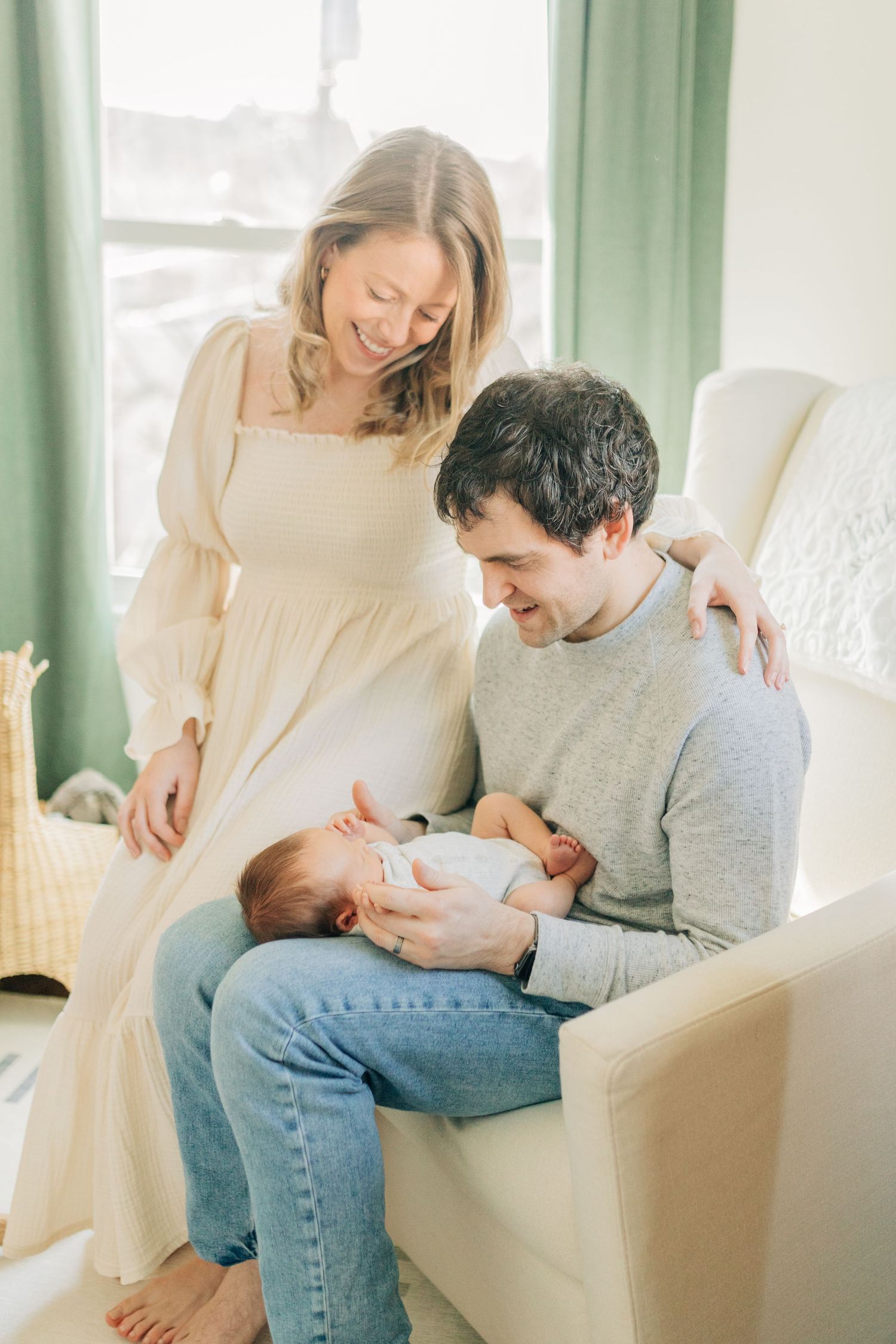 Intimate family moment with newborn in bright living room setting.