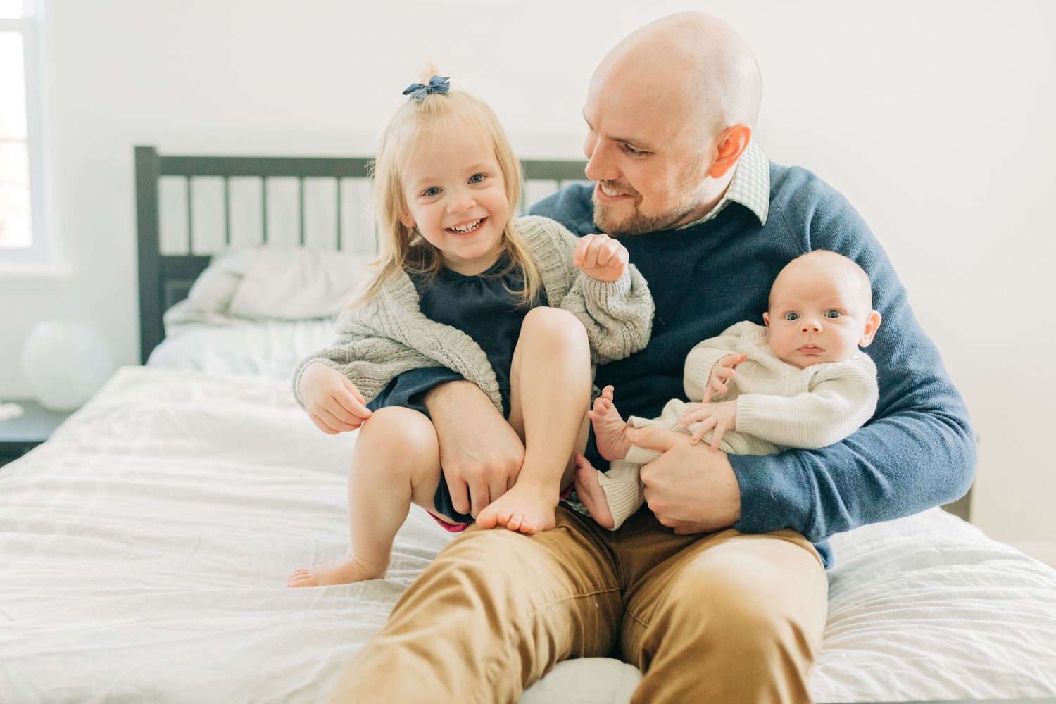 Family sharing happy moments together on bed with toddler and infant.