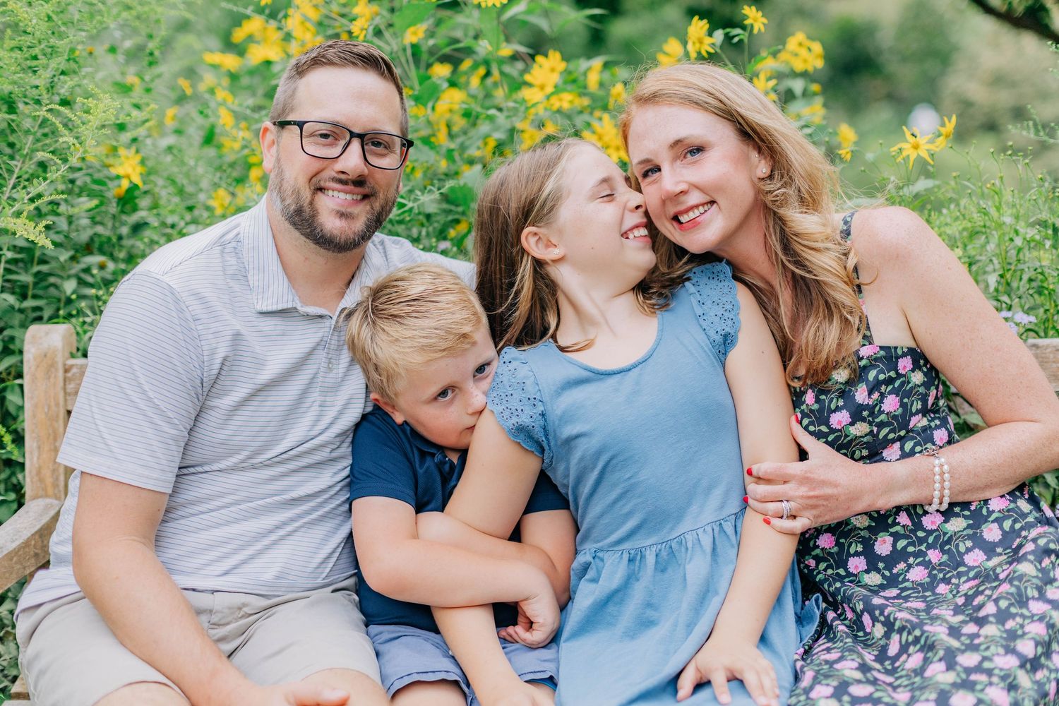 Family portrait series with coordinated blue and grey outfits in a flowering garden.
