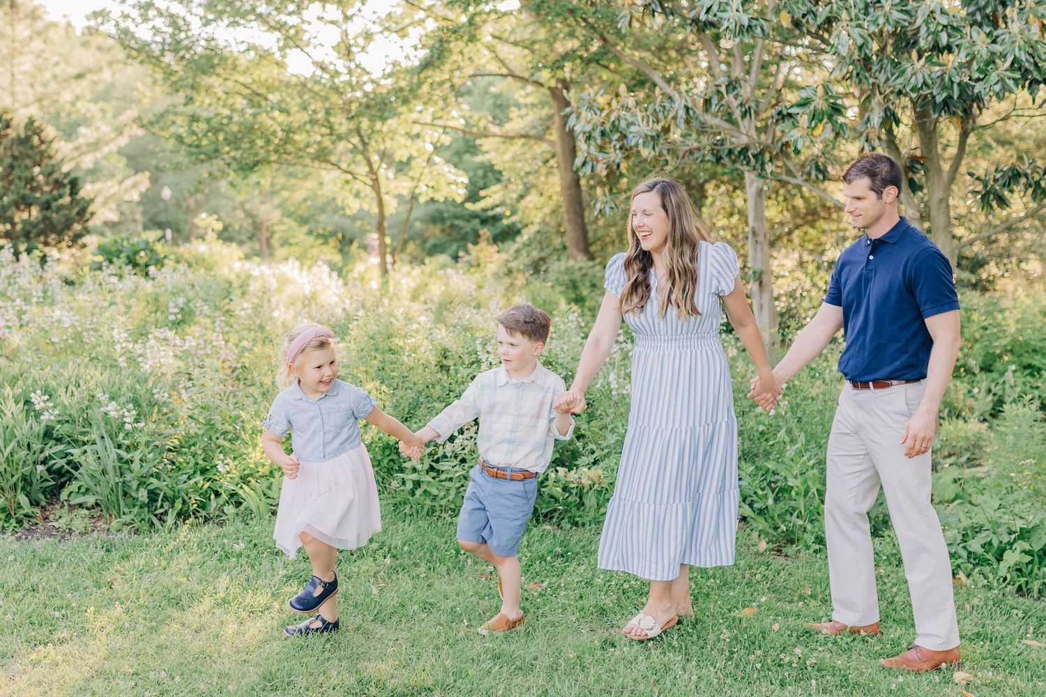 A family walks together through a sunlit garden during a photo session.